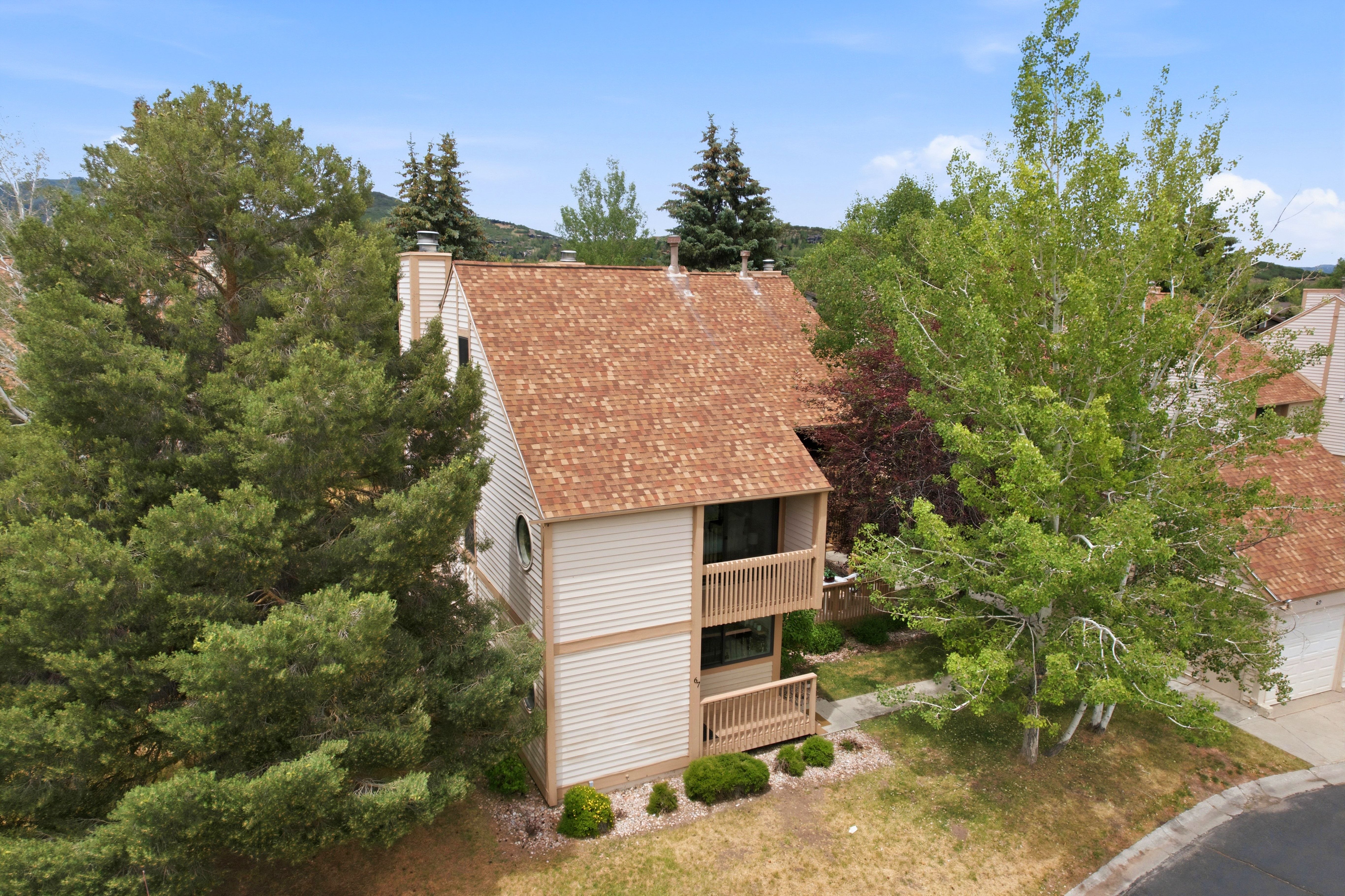 Multi-level exterior with light-toned siding and a brown shingle roof