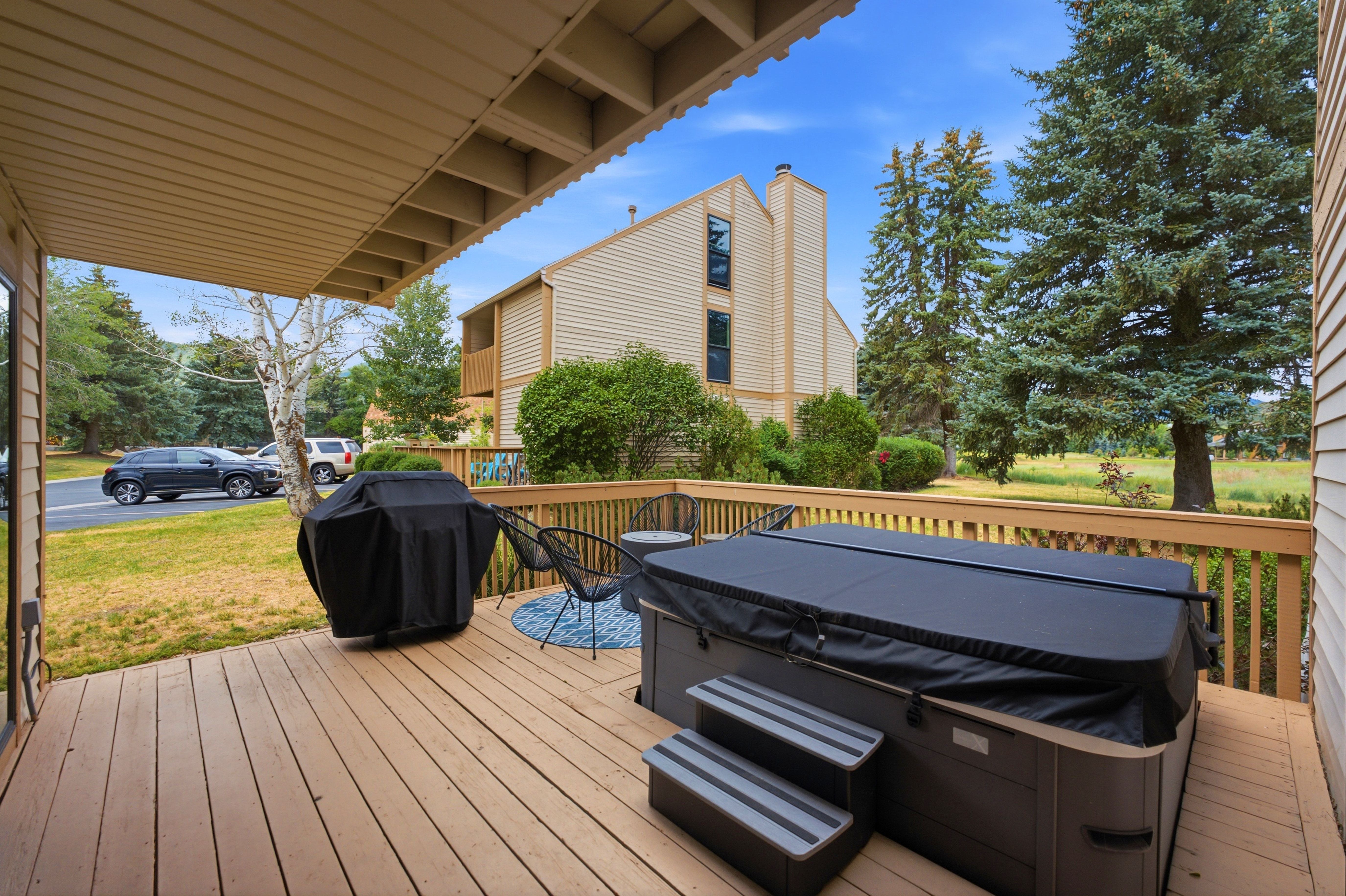 Expansive outdoor deck featuring wood-finish flooring, a hot tub with cover and steps, and a privacy railing