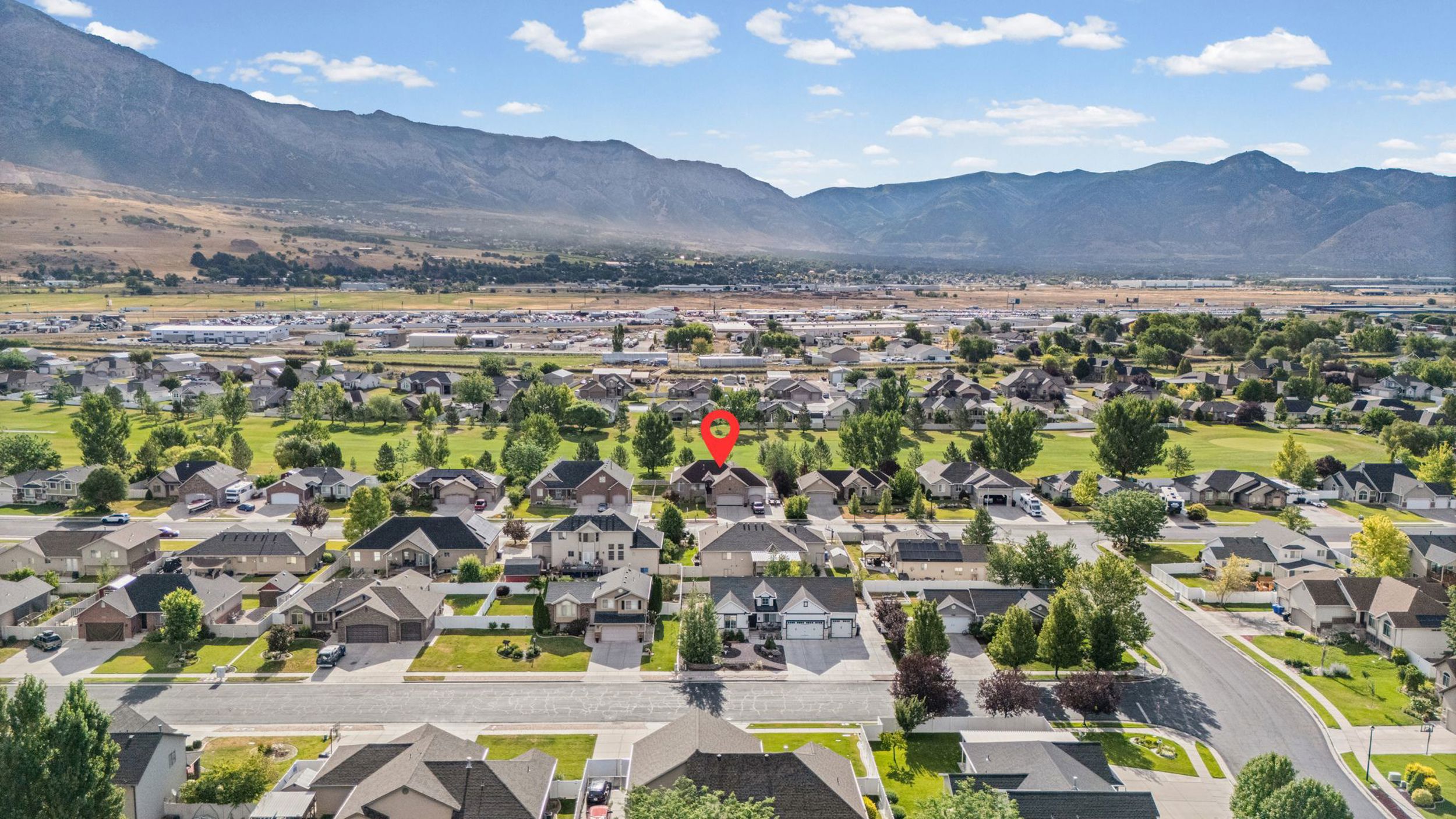 Aerial perspective of a residential neighborhood with mountain backdrops and a golf course