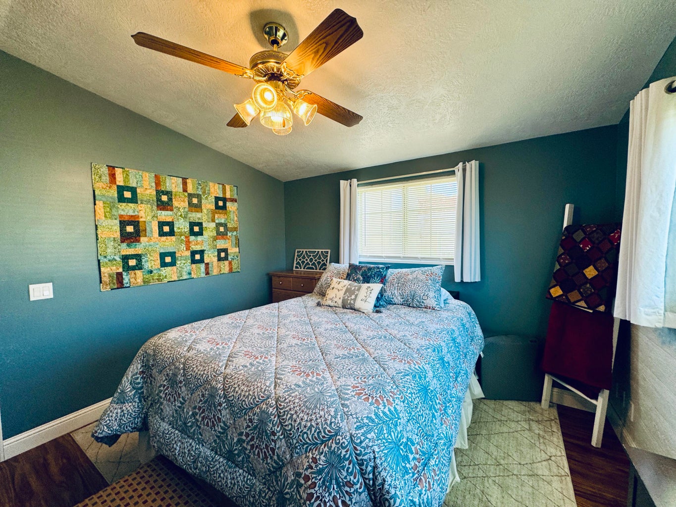 Room featuring wood-finish flooring, a ceiling fan with integrated lighting, and a window with blinds