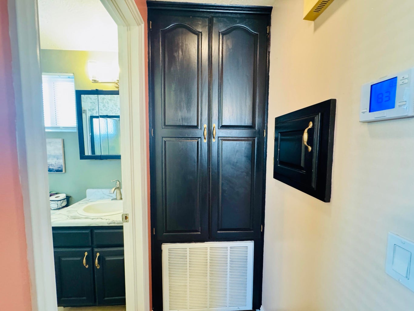 Built-in storage cabinet with black paneled doors and gold-toned hardware