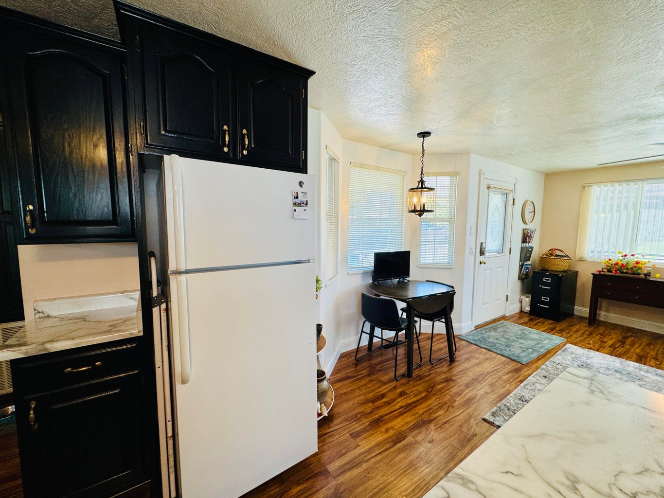 Kitchen area featuring dark cabinetry, a white refrigerator, and light-colored countertops