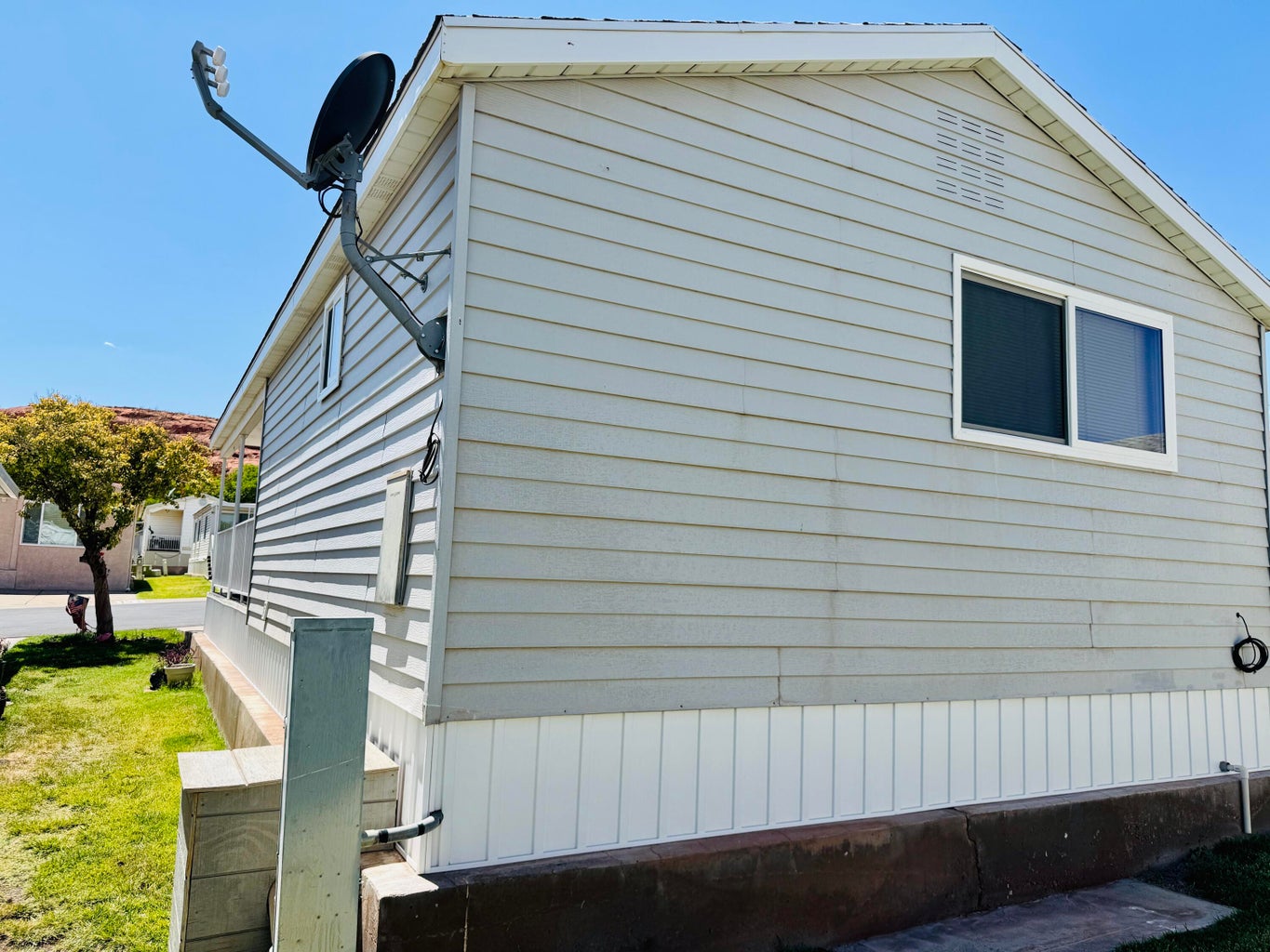 Light-colored horizontal siding with a white trim window and a peaked roofline