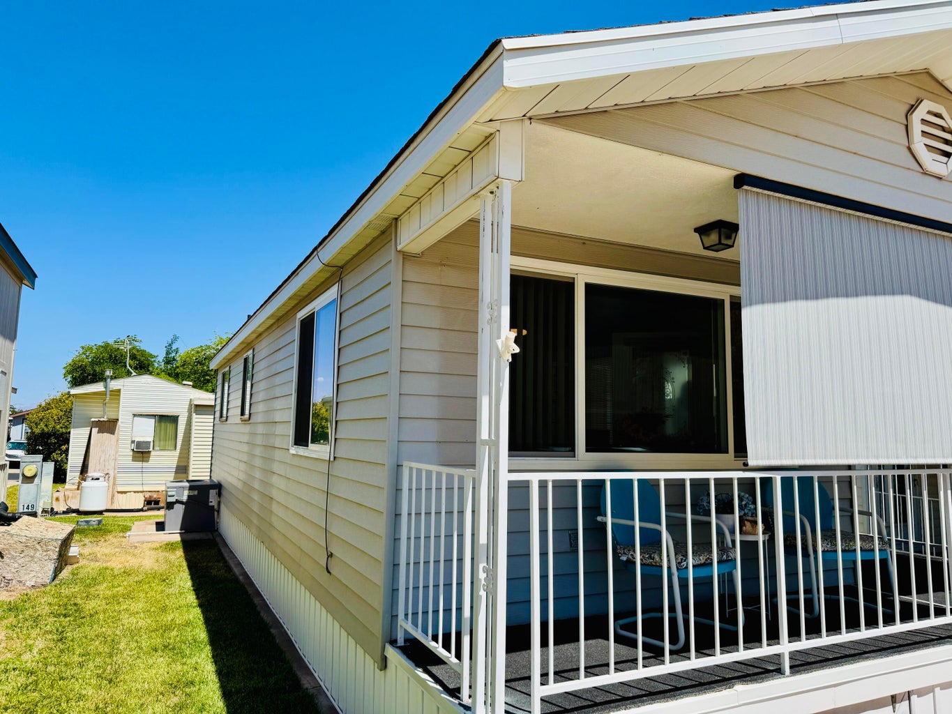 Exterior featuring neutral siding, a covered porch with white railing, and multiple windows