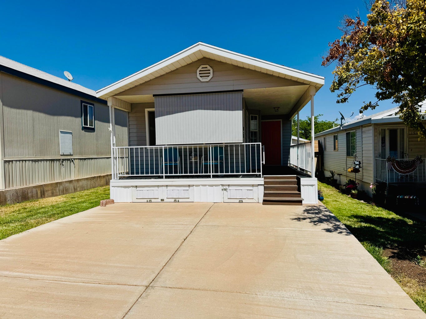 Single-story residence featuring a covered front porch with white railing, a vibrant red entry door, and a light gray exterior