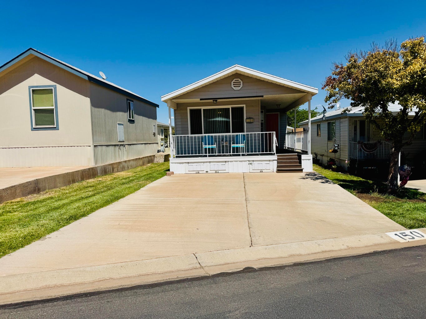 Single-story residence featuring a covered front porch with white railing, sliding glass door entry, and an extended concrete driveway