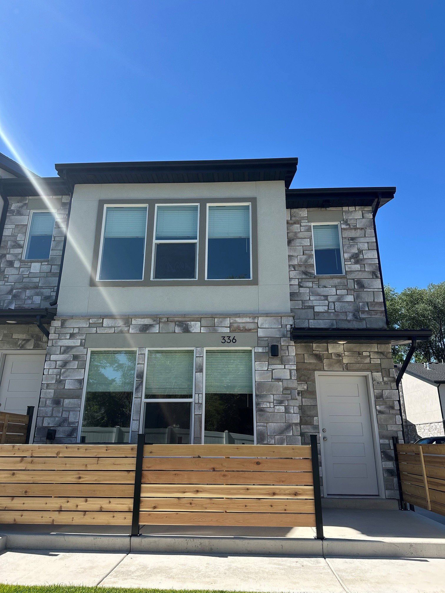 Contemporary townhome exterior featuring a stone and stucco facade, a flat roofline, and multiple large windows