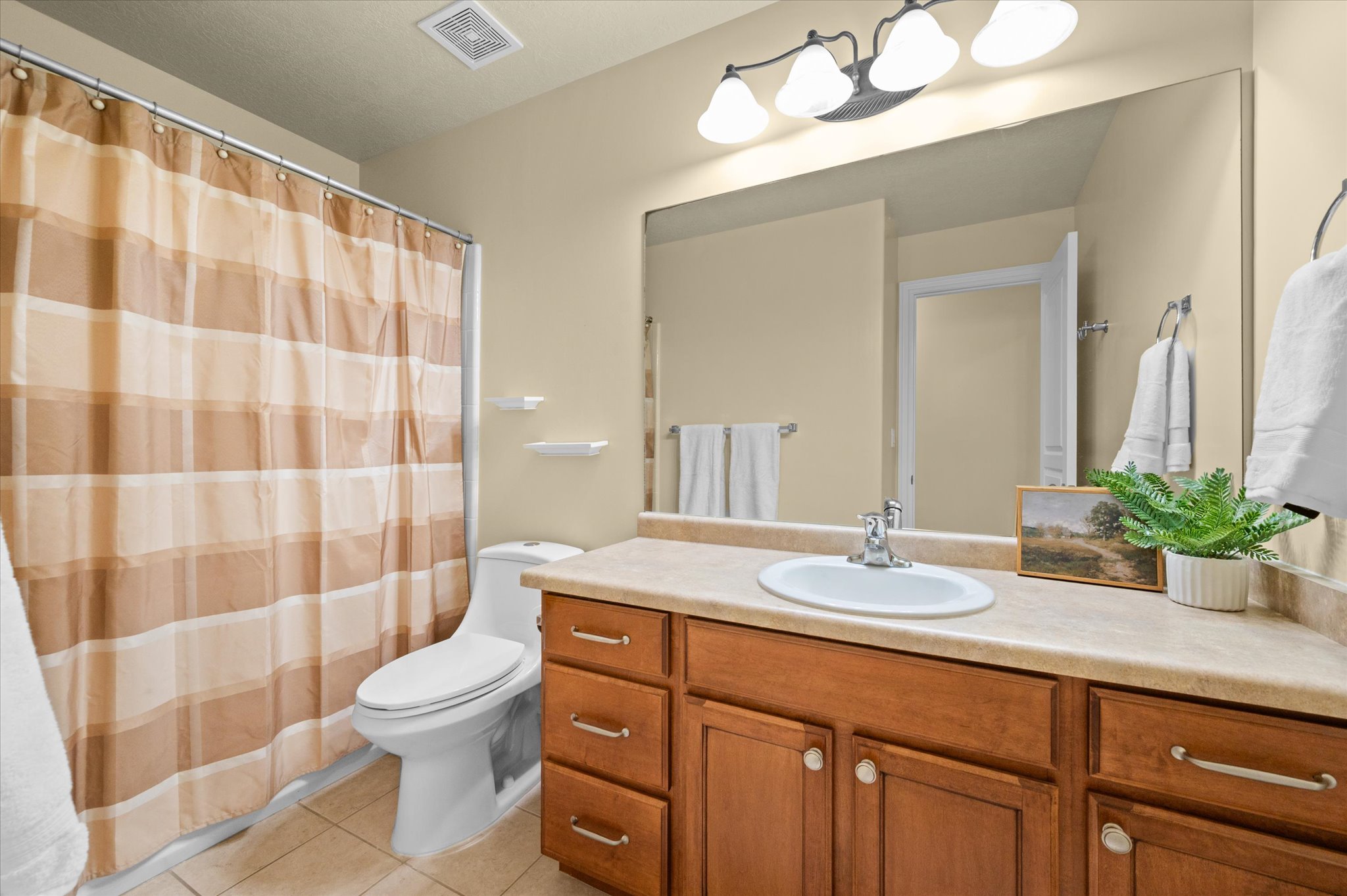 Bathroom featuring a single vanity with wood cabinetry, a light-toned countertop, and an oval sink