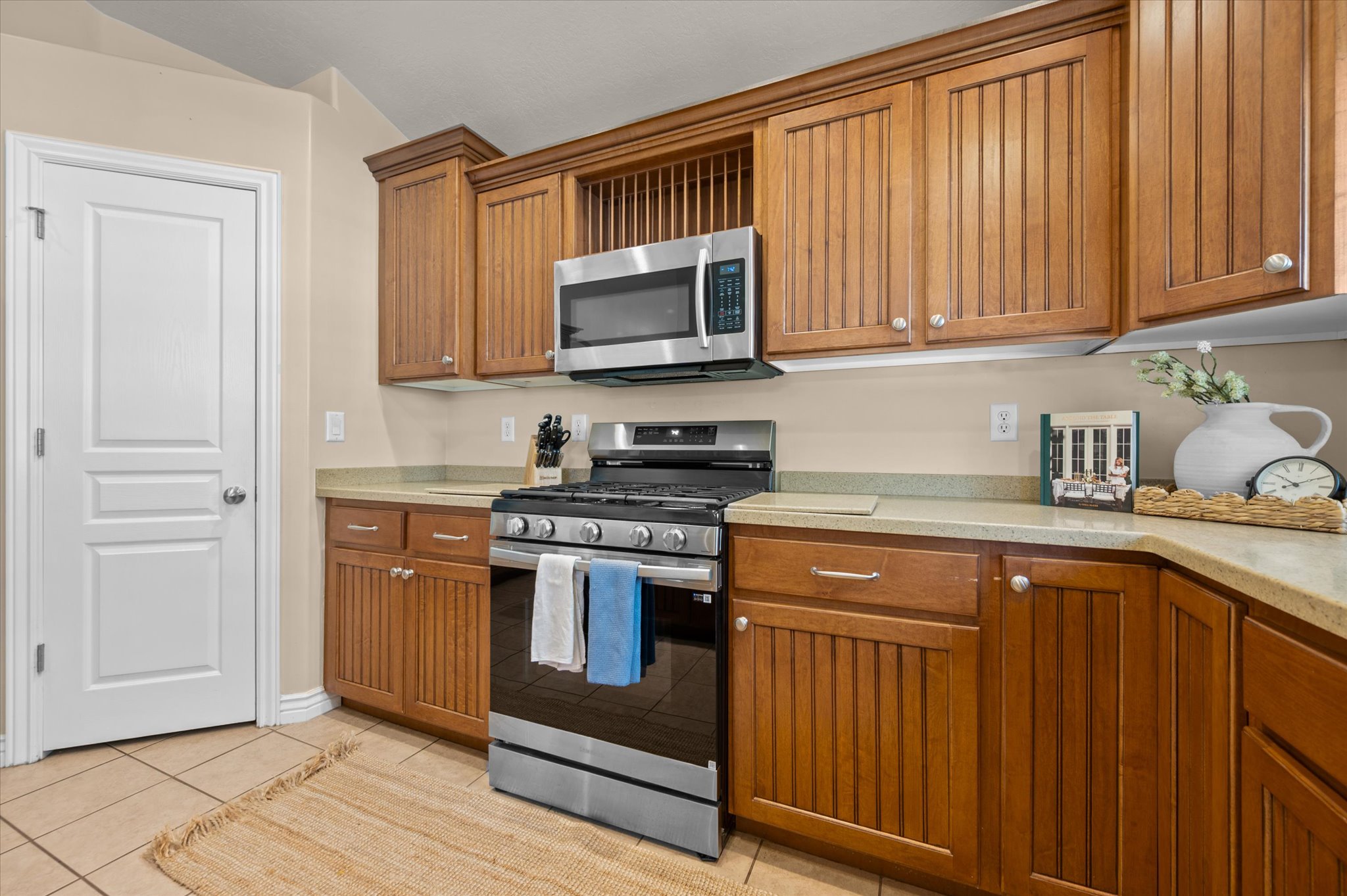 Kitchen featuring wood-finish cabinetry, stainless steel microwave, gas range with oven, and light-toned countertops