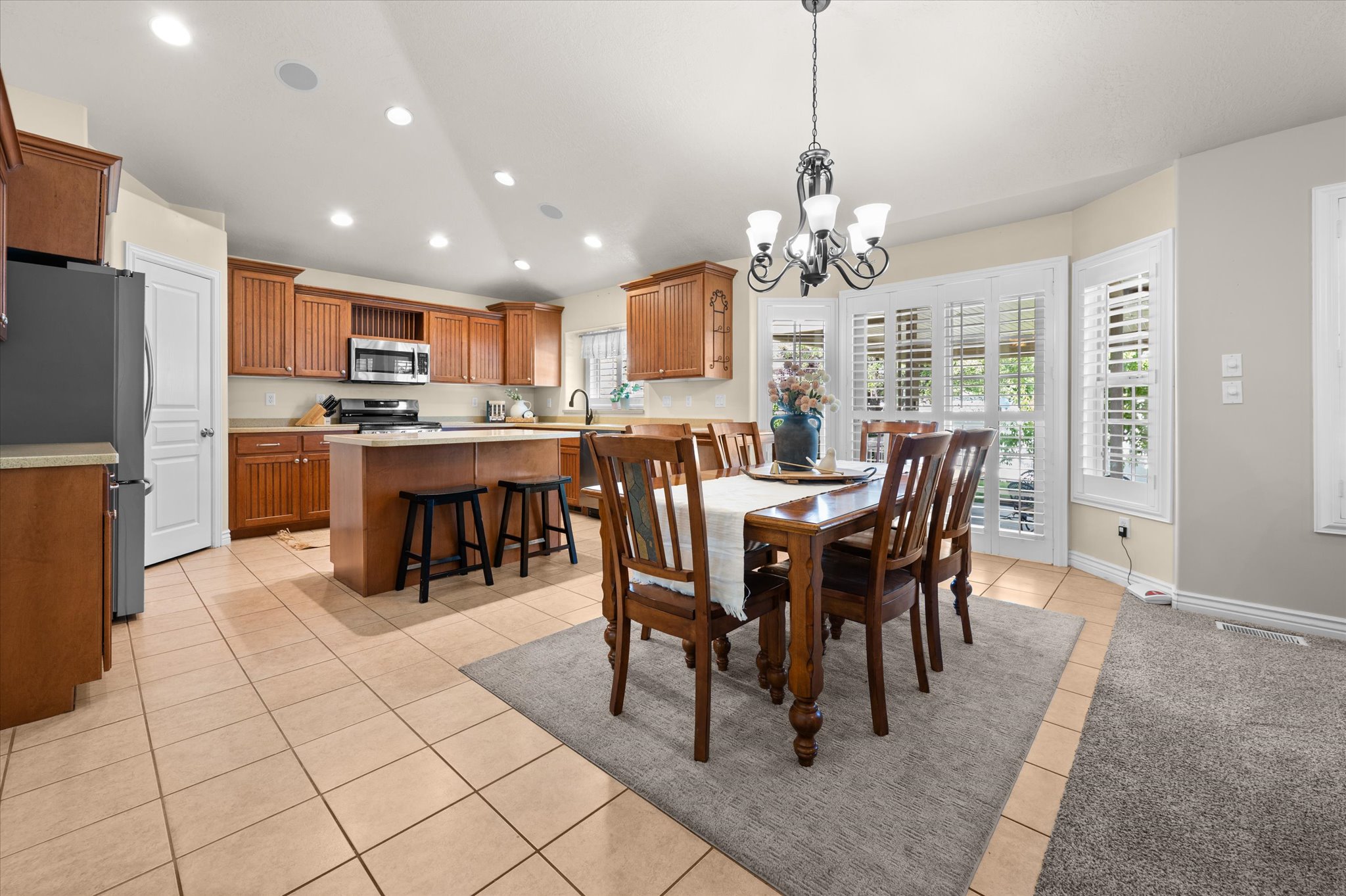 Open-concept kitchen and dining area featuring warm wood cabinetry, a central island with bar seating, and stainless steel appliances