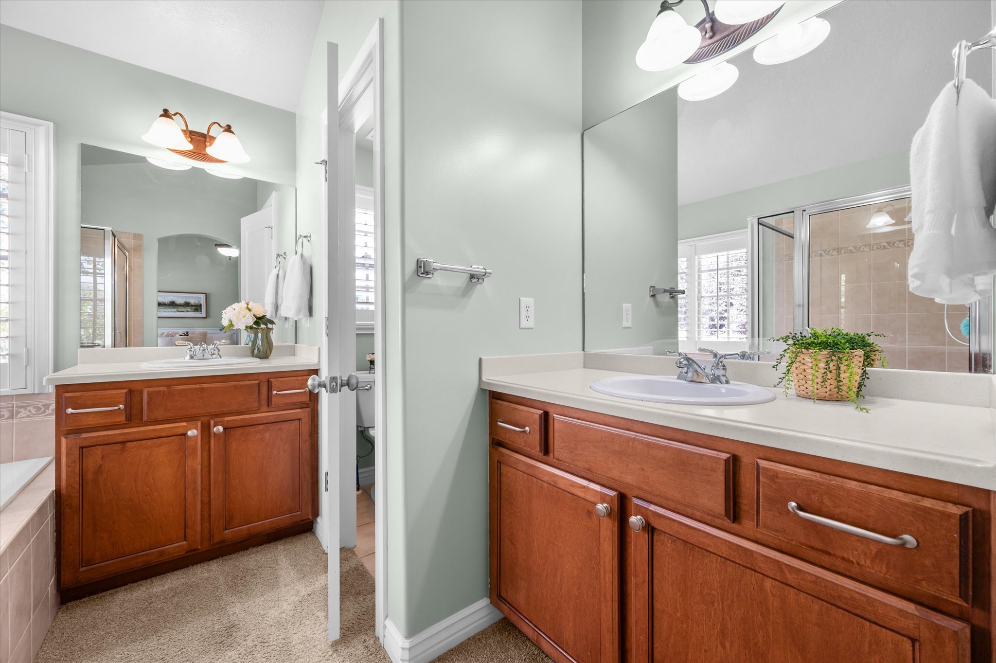 Dual vanity area with wood-finish cabinetry, integrated sinks, and neutral countertops