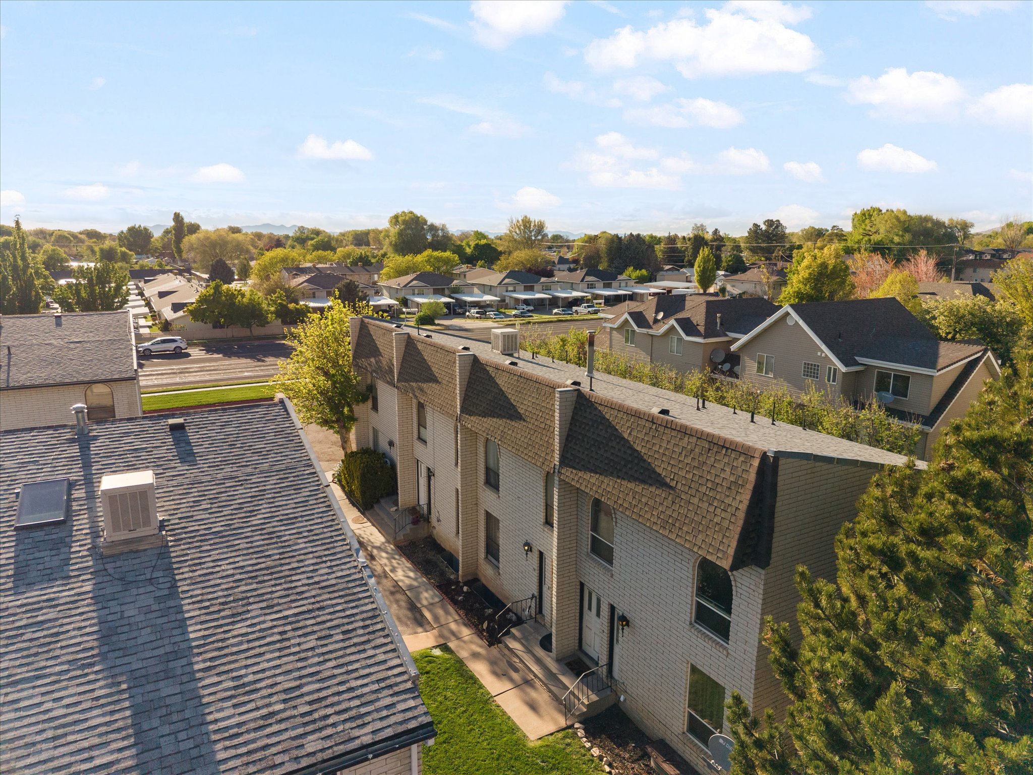 Row of attached townhome-style residences featuring light-colored brick facades and dark shingle roofs