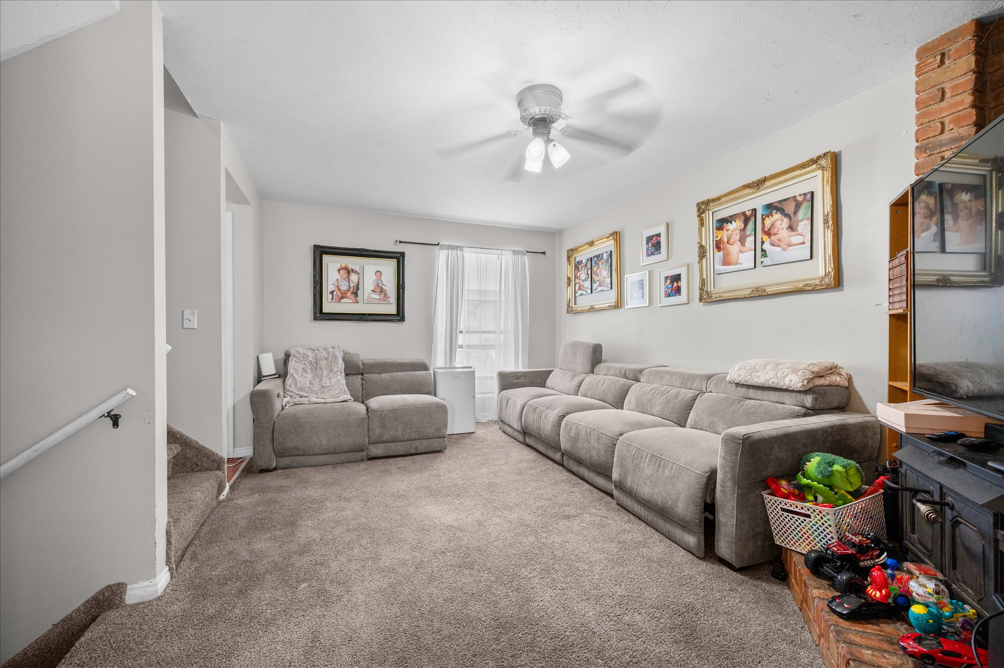 Carpeted living room featuring light gray walls and a ceiling fan