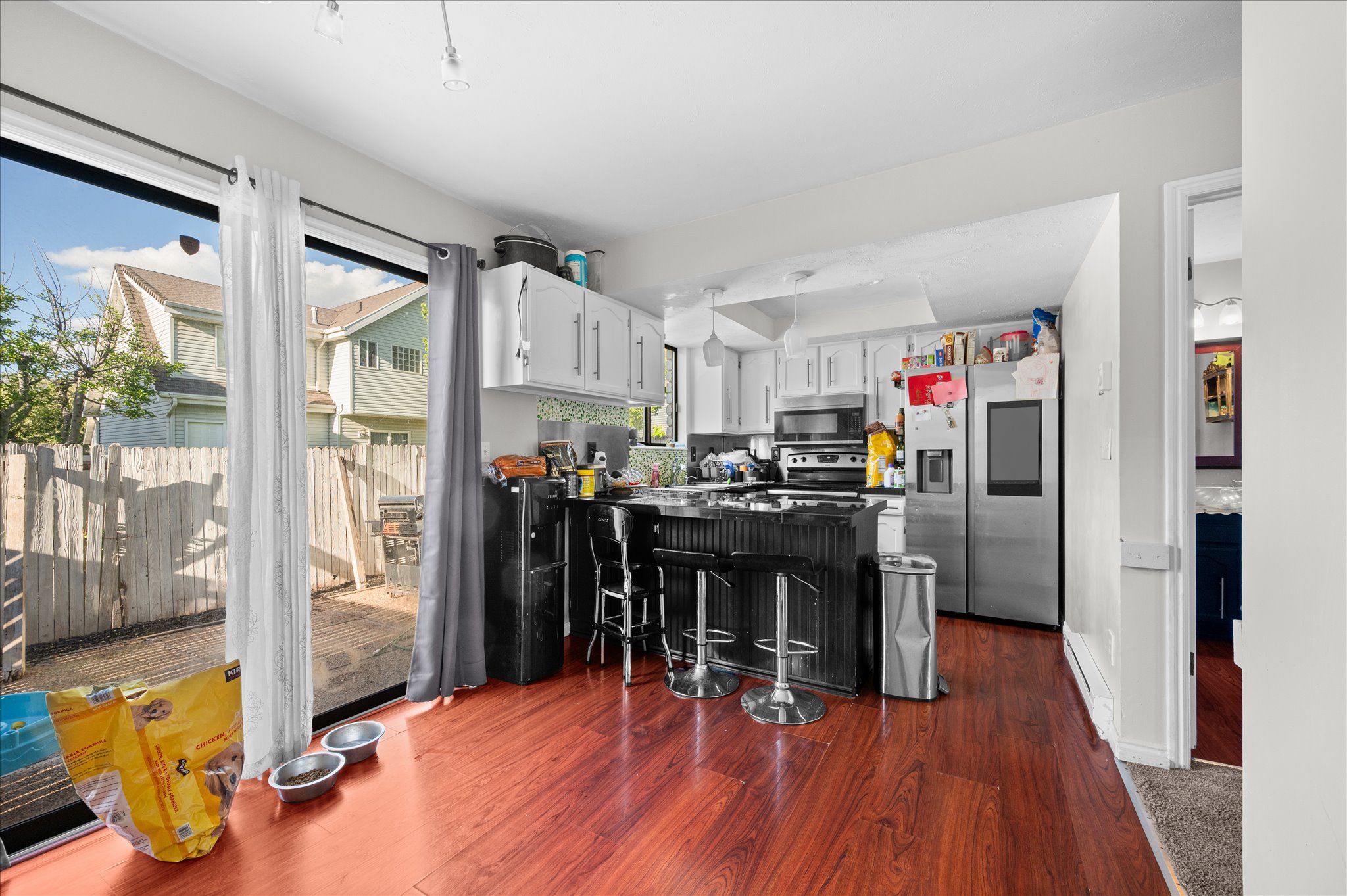 Kitchen featuring wood-finish flooring, white upper cabinetry, stainless steel appliances, and a breakfast bar with seating