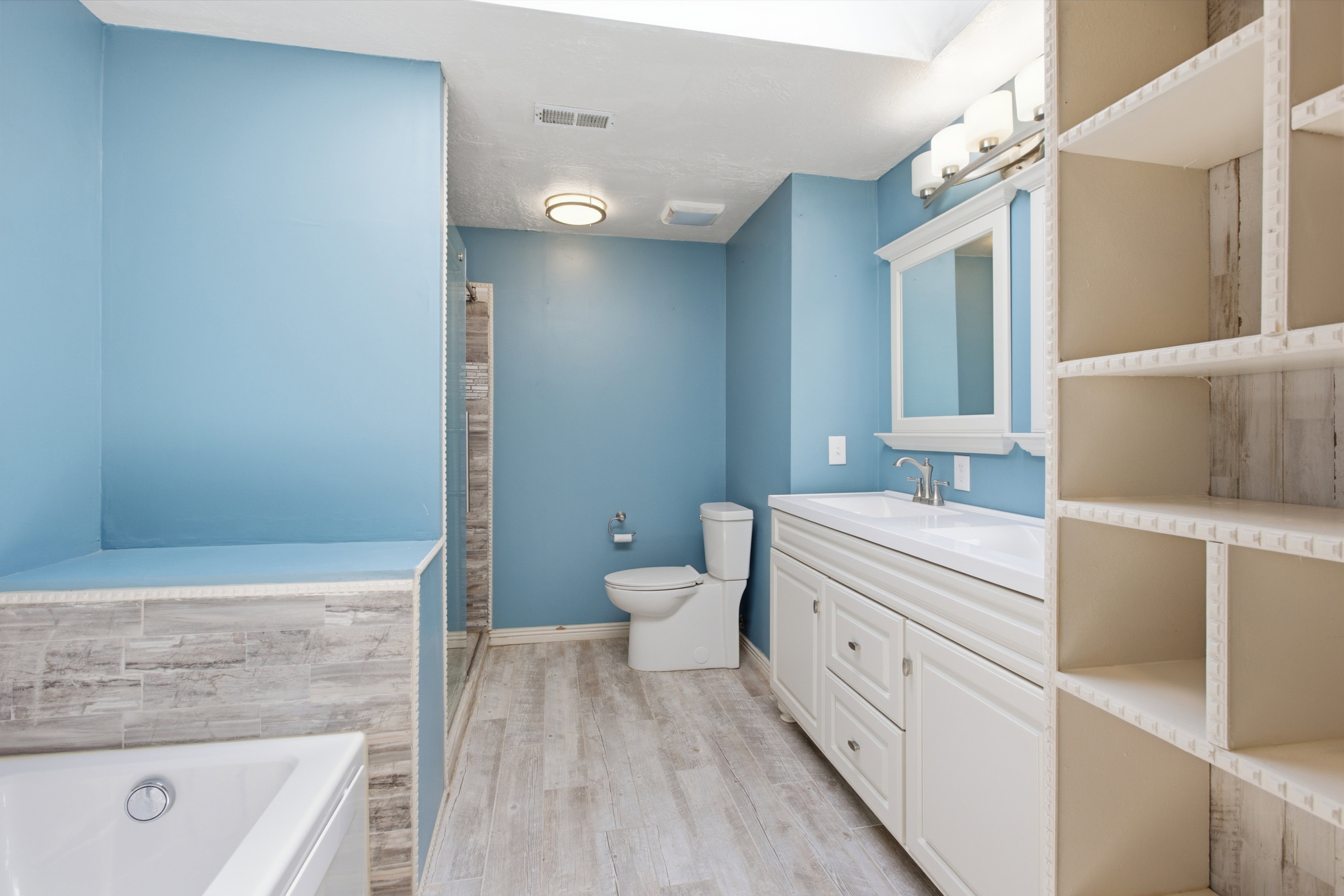 Bathroom featuring a white vanity with integrated sink, a framed mirror, and a wall-mounted light fixture