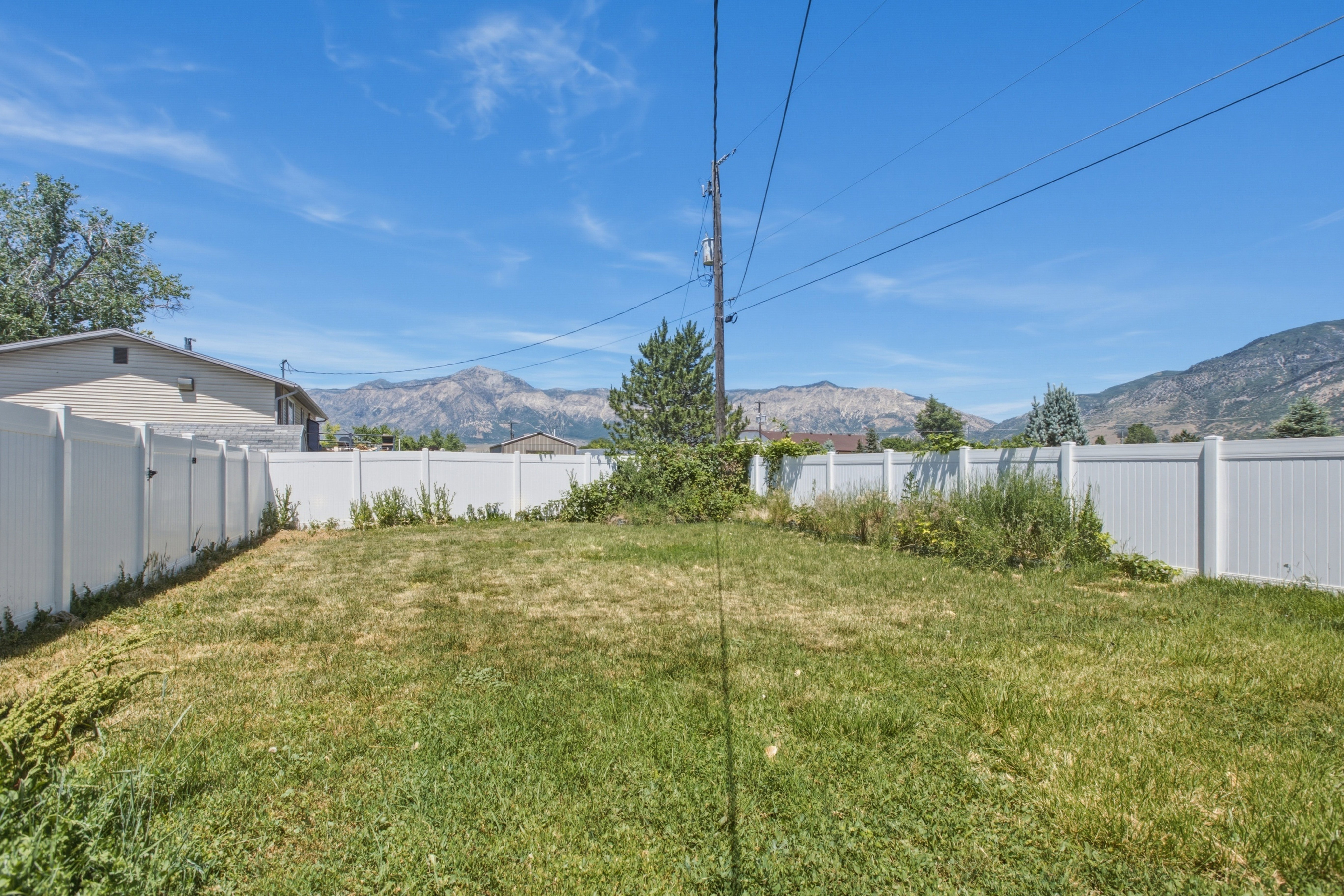 Expansive grassy yard with full white privacy fencing