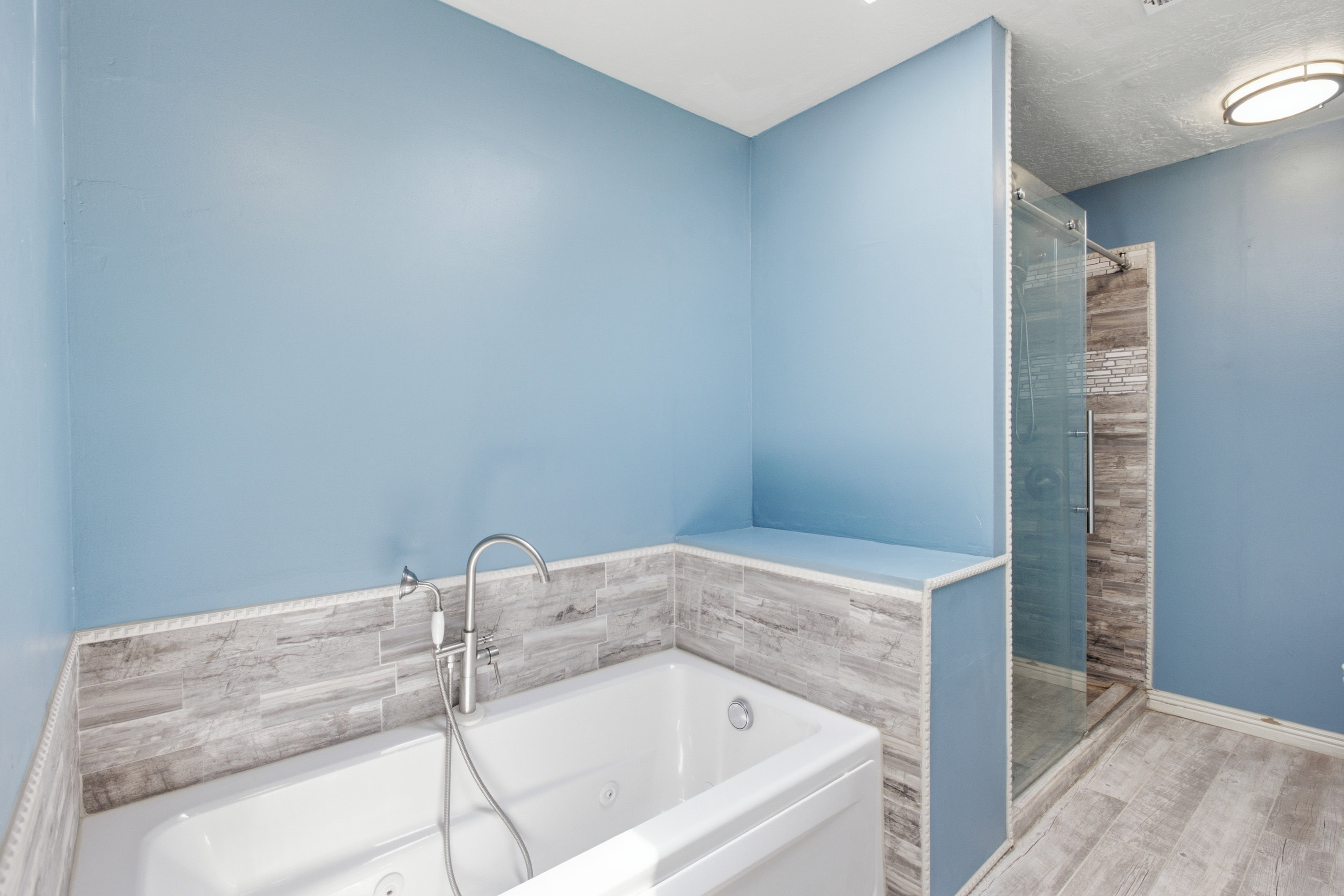 Freestanding soaking tub with chrome fixtures, tiled surround, and integrated shelving