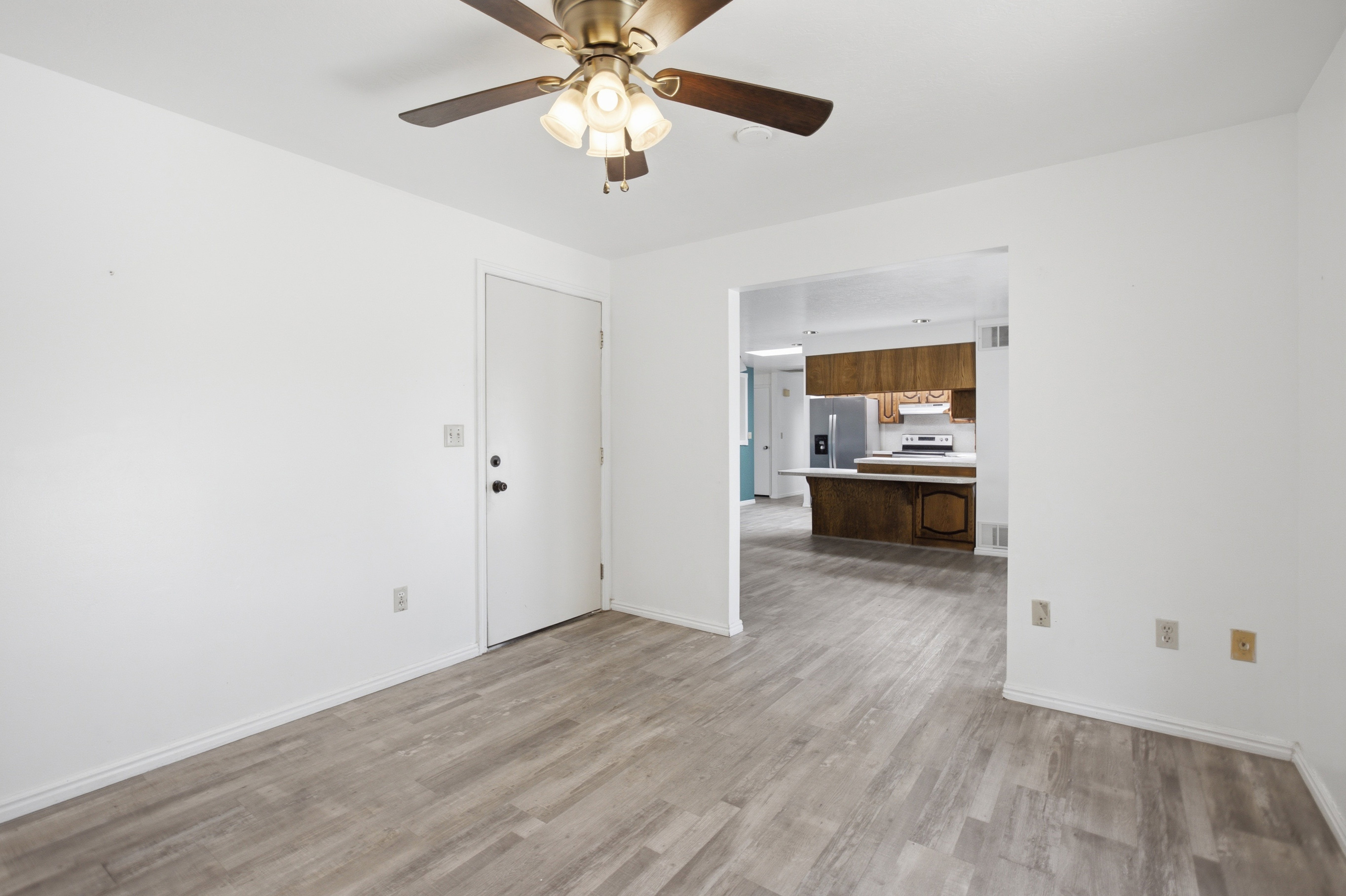 Wood-finish flooring throughout, bright white walls, and a ceiling fan with integrated lighting
