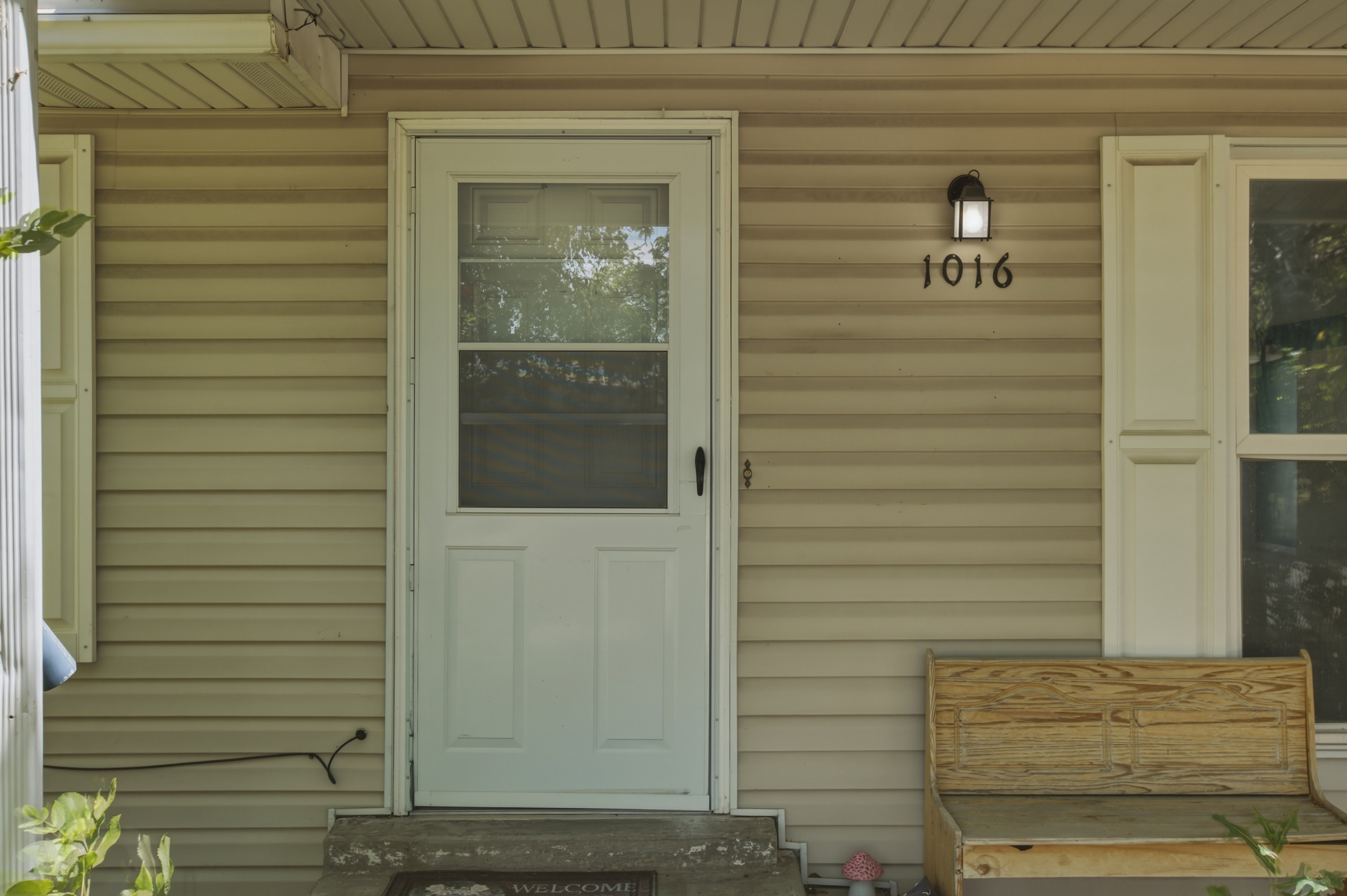 Front exterior featuring beige horizontal siding and a white entry door with an integrated screen