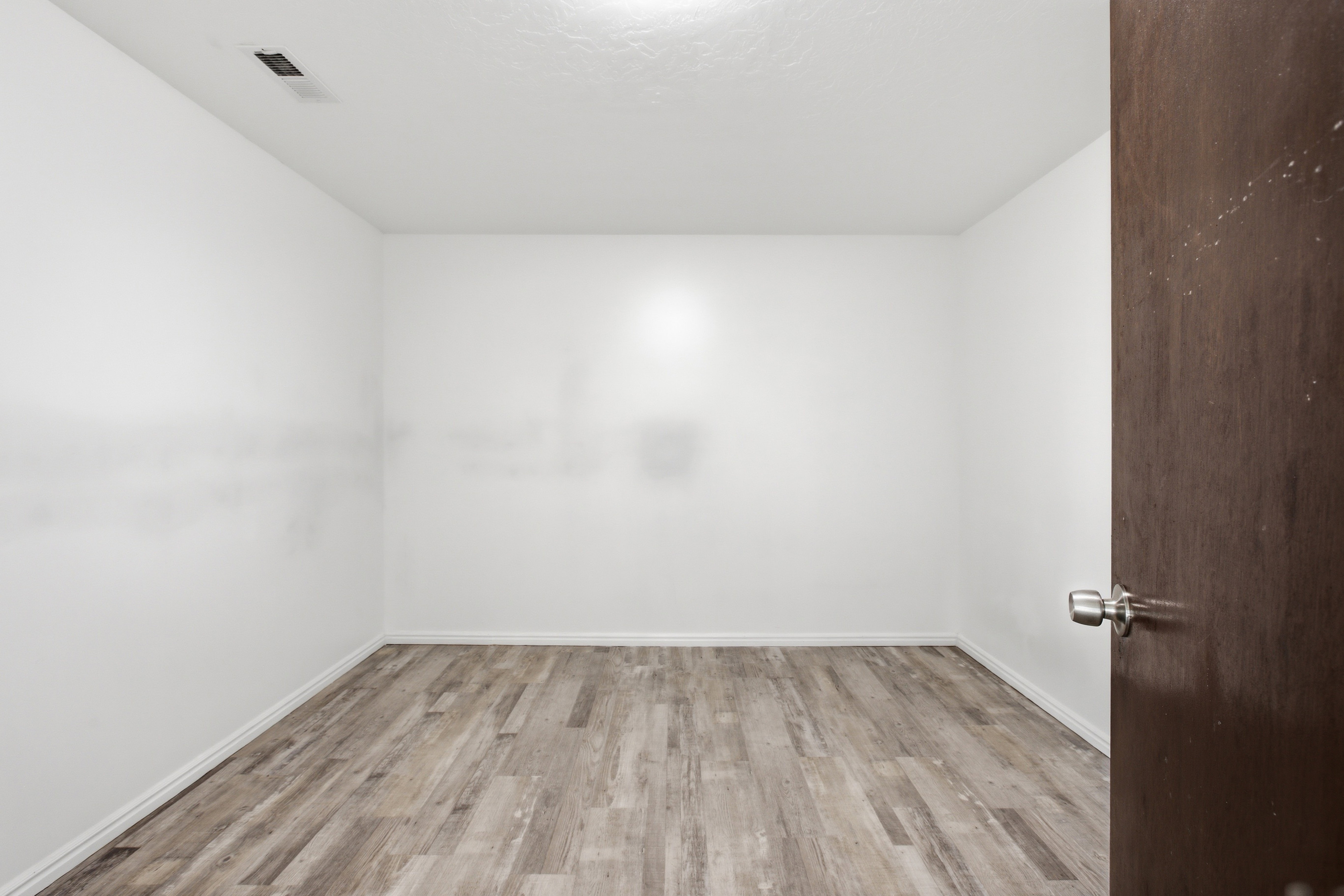 Room with wood-finish flooring, white walls, and white baseboards, Could be a den, office, storage!