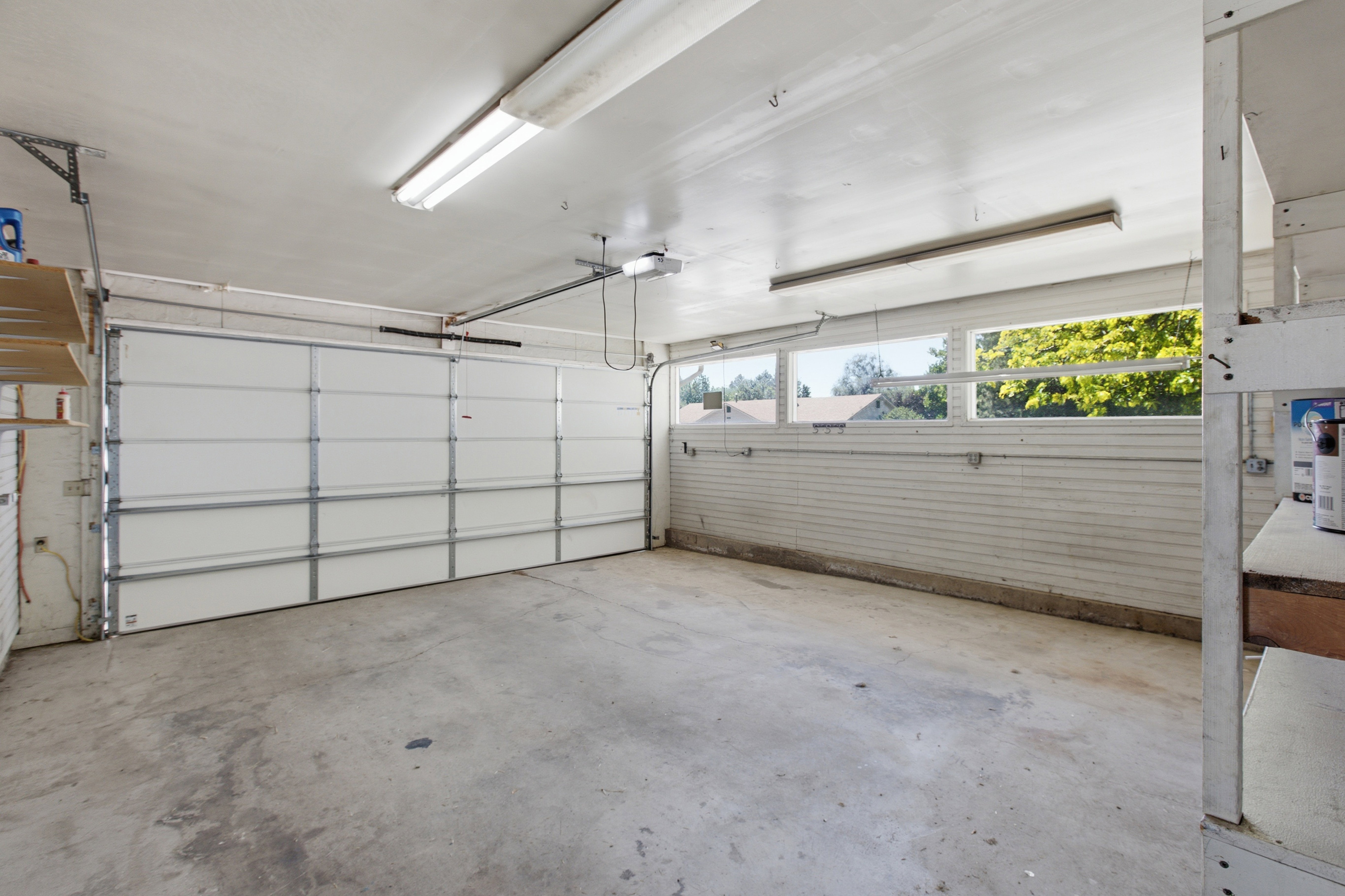 Spacious garage featuring a sectional overhead door, concrete flooring, and ample natural light from horizontal windows