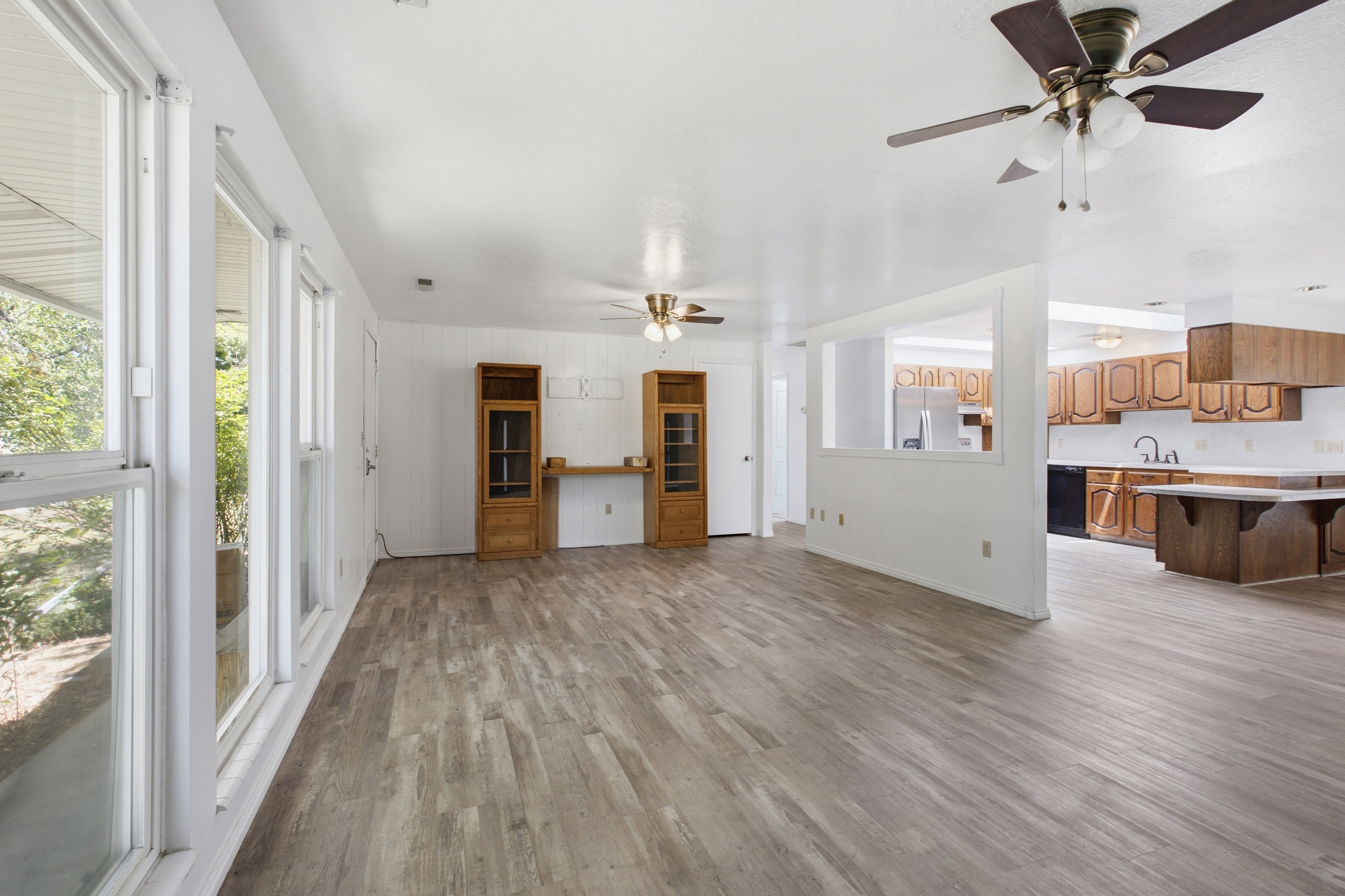 Spacious open-concept interior featuring light wood-finish flooring and multiple windows