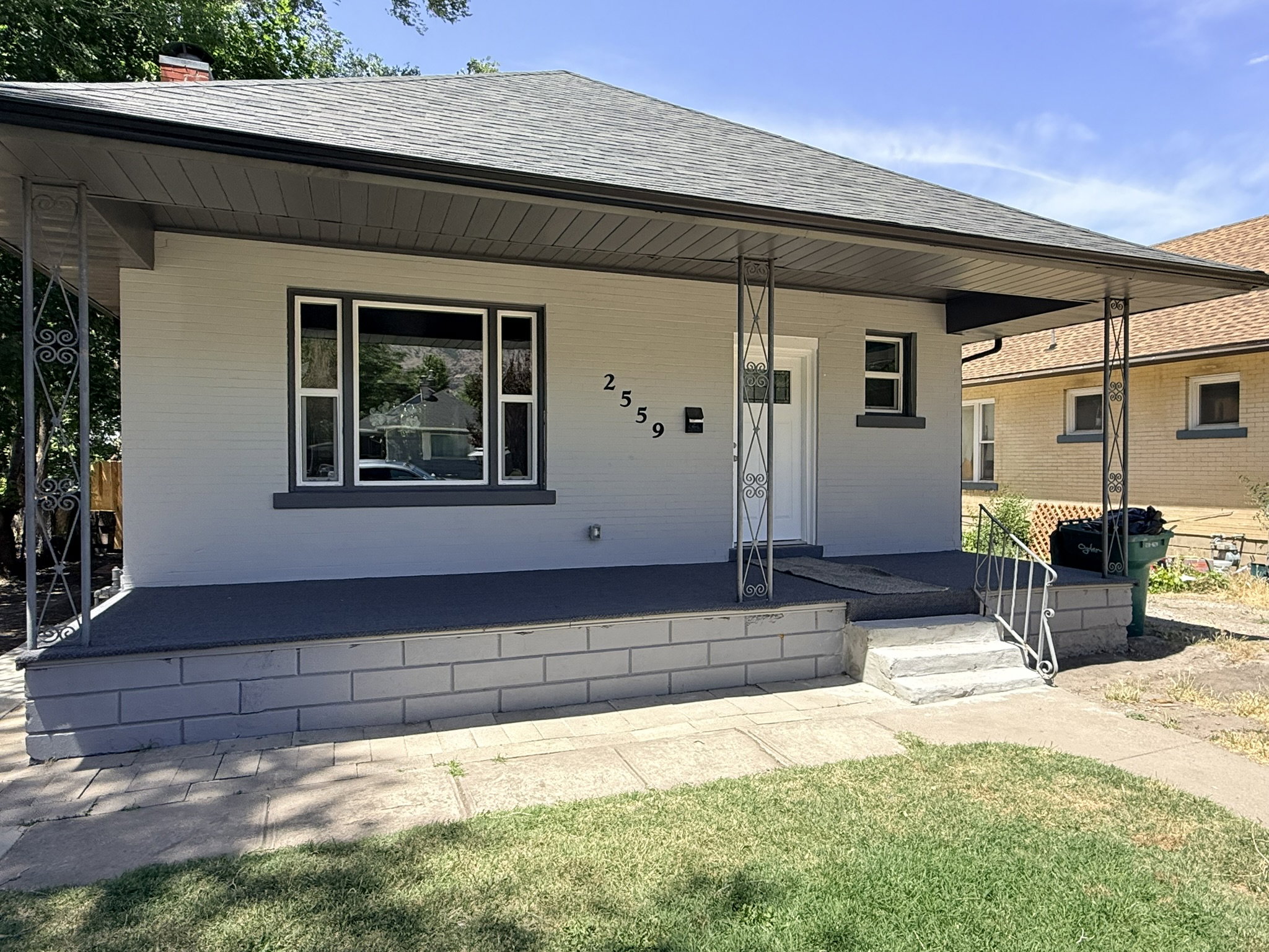 Light gray exterior with dark trim and a covered front porch featuring decorative metal columns
