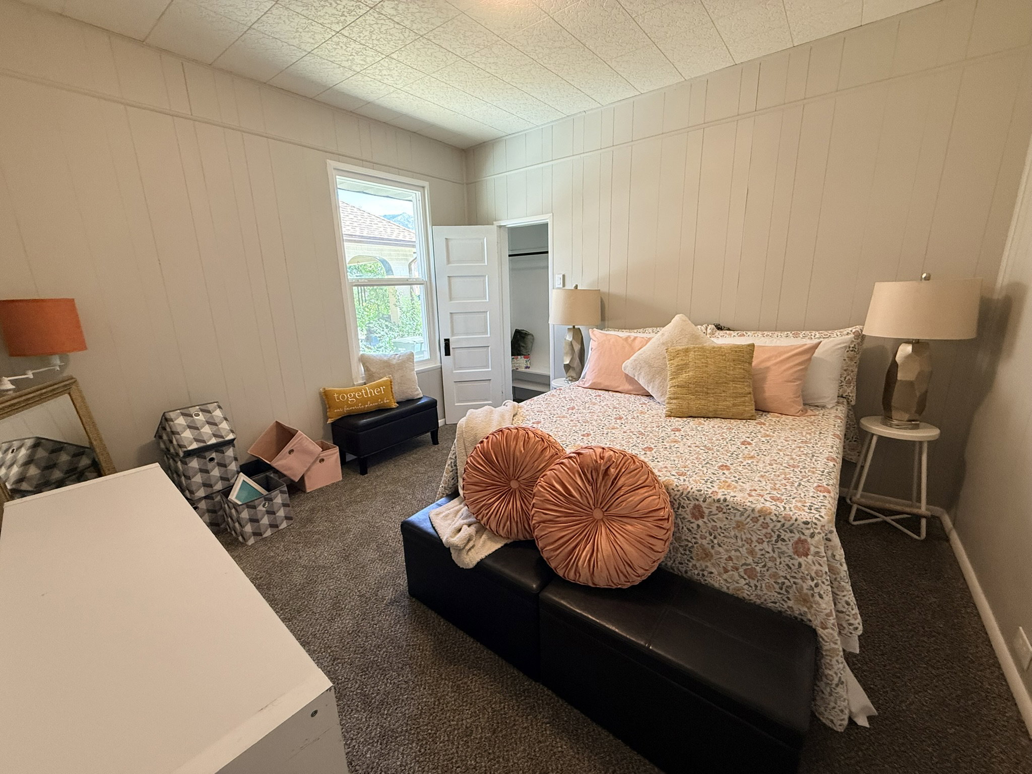 Spacious room featuring vertical paneling, a large window, textured ceiling, and neutral carpet flooring