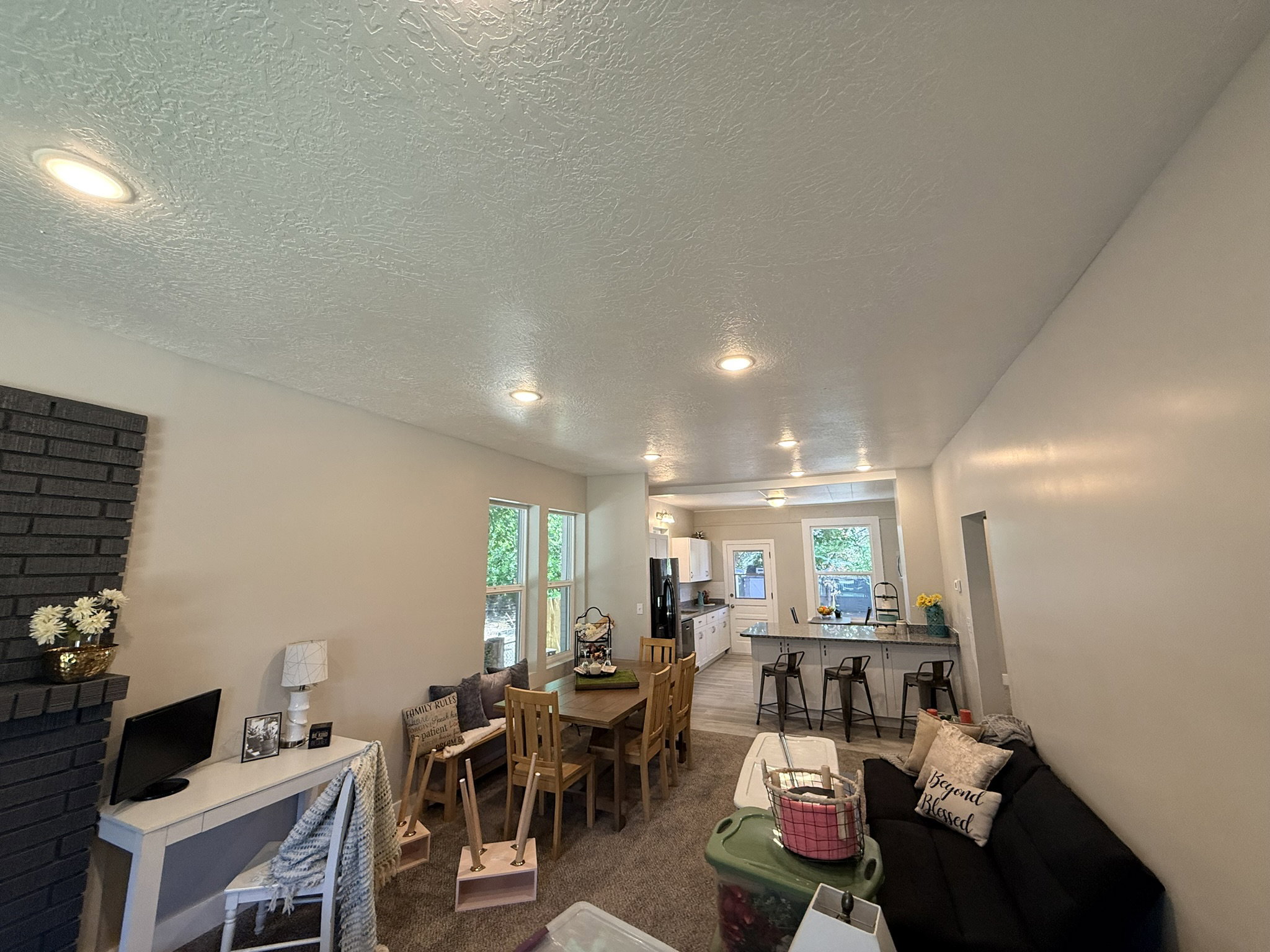 Open-concept living area featuring recessed lighting, a dark brick fireplace, and light-colored walls