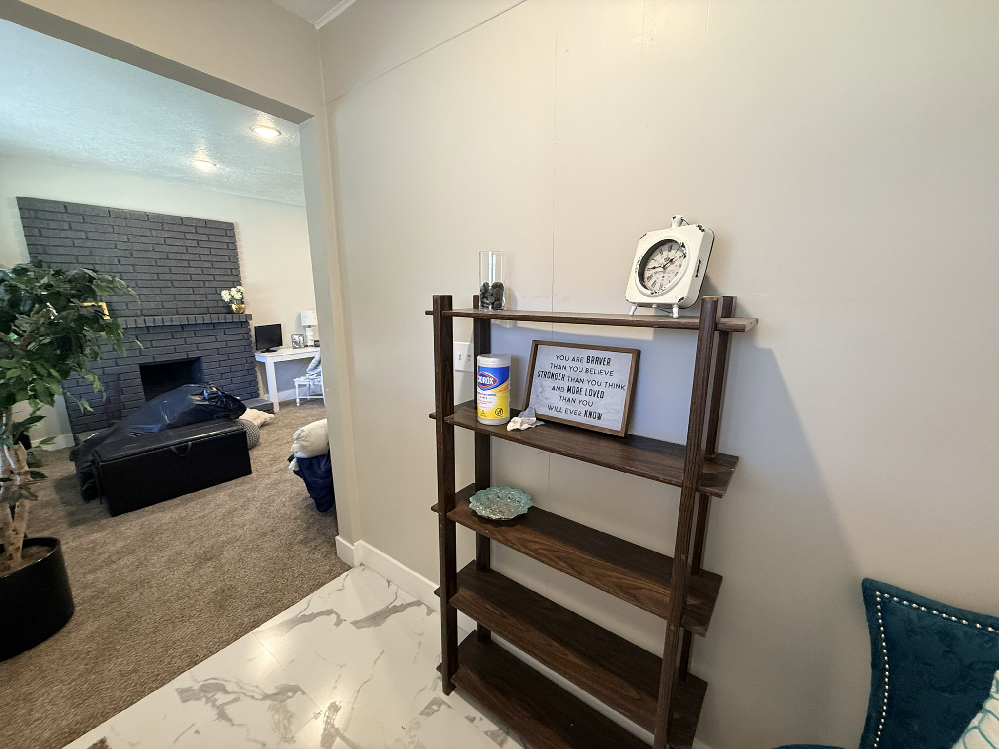 Interior space featuring a dark-stained wood shelving unit, light neutral wall paint, and white marble-look tile flooring