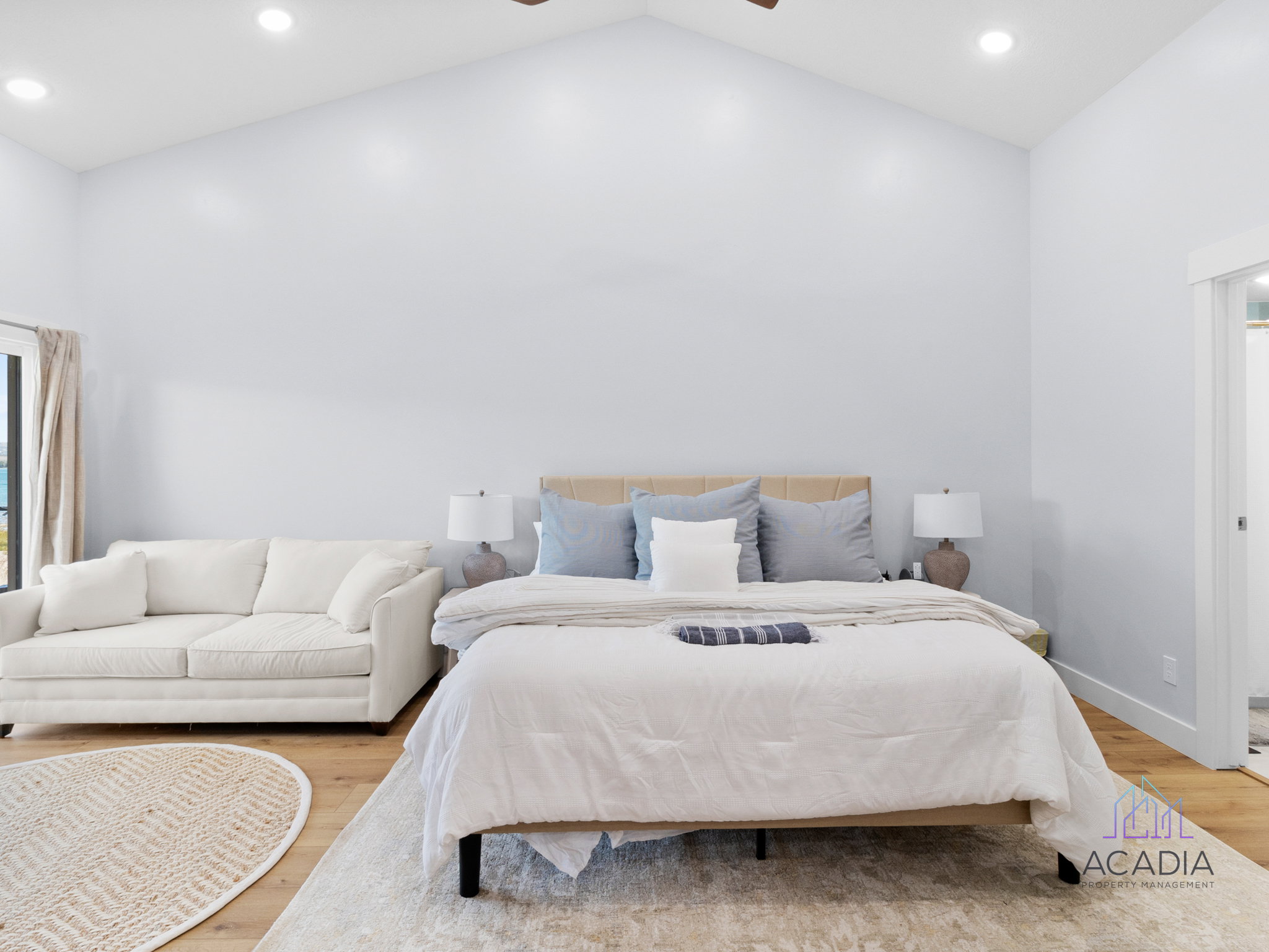 Spacious room featuring vaulted ceilings, recessed lighting, wood-finish flooring, and a large window with exterior scenery