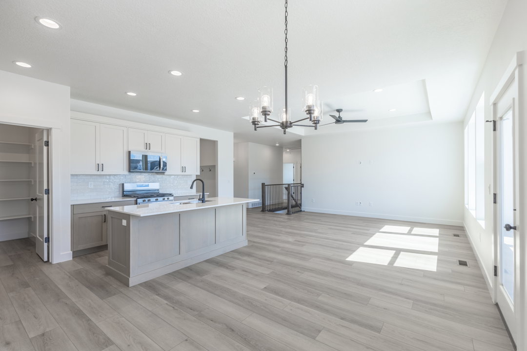 Open-concept living space with light wood-finish flooring, recessed lighting, and a tray ceiling