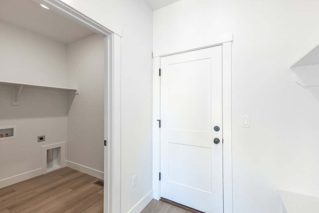 Dedicated laundry area featuring a built-in shelf, appliance hookups, wood-finish flooring, and crisp white trim