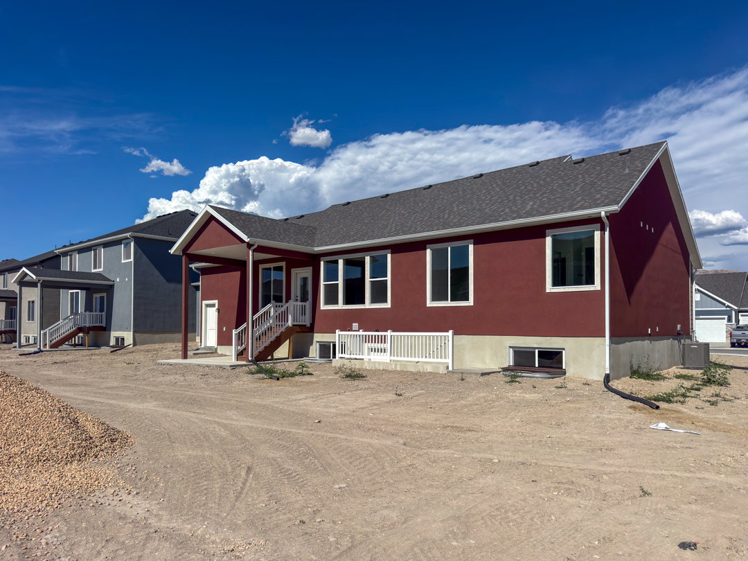 Red-hued exterior featuring multiple windows and a covered patio