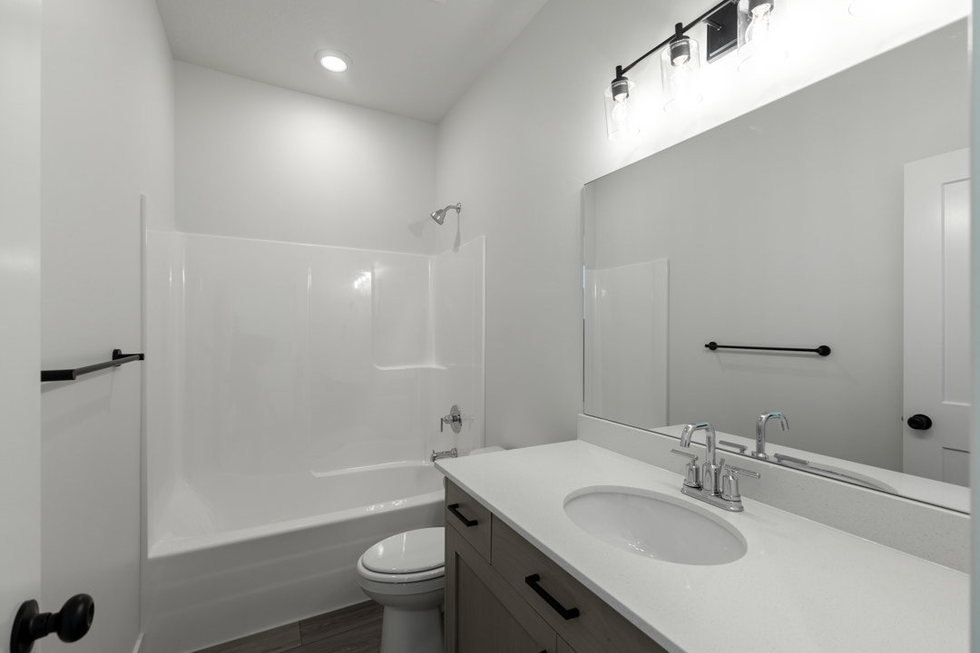Bathroom featuring a single vanity with stone-look countertop, integrated sink, and wood-finish cabinetry