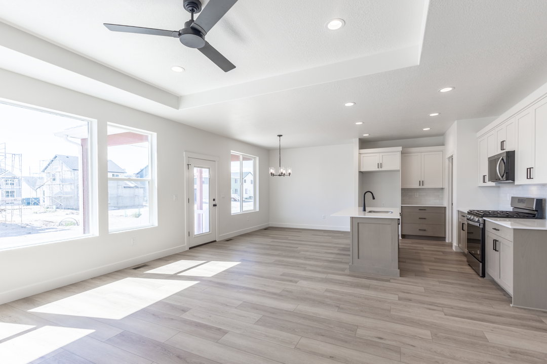 Open-concept living space featuring wood-finish flooring, recessed lighting, and a tray ceiling with a ceiling fan