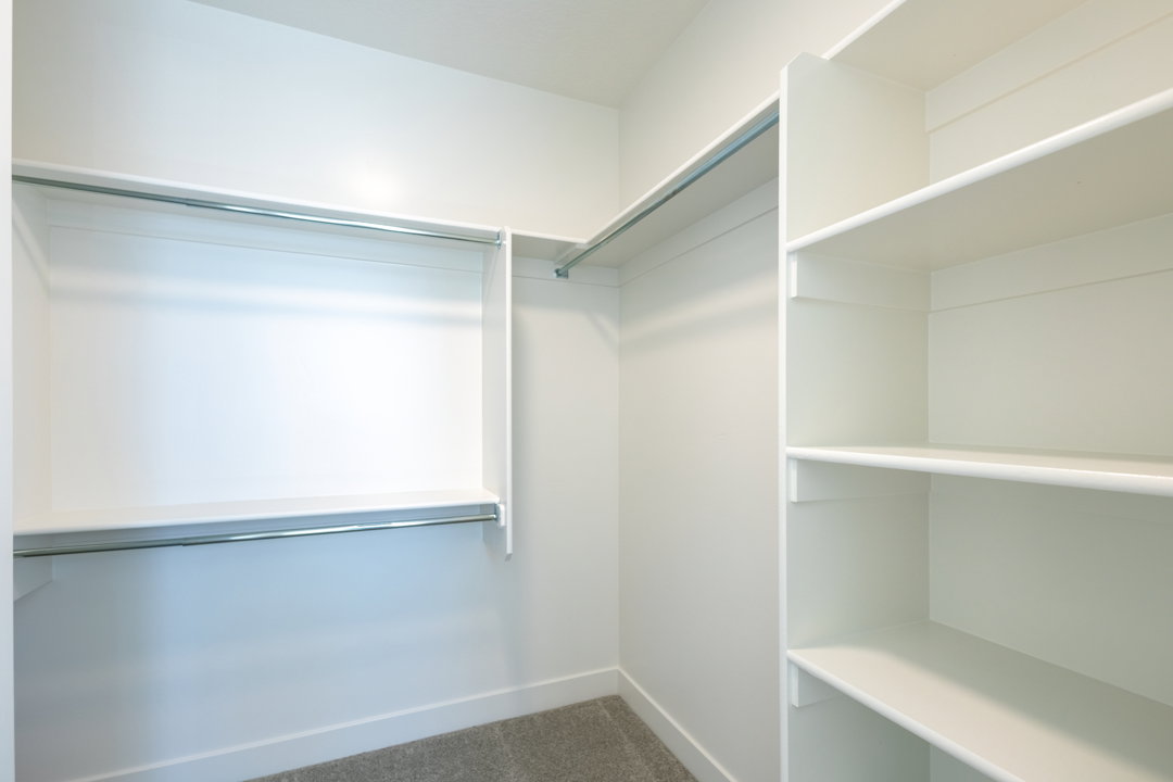Walk-in closet featuring built-in shelving, dual hanging rods, and light-toned carpeting