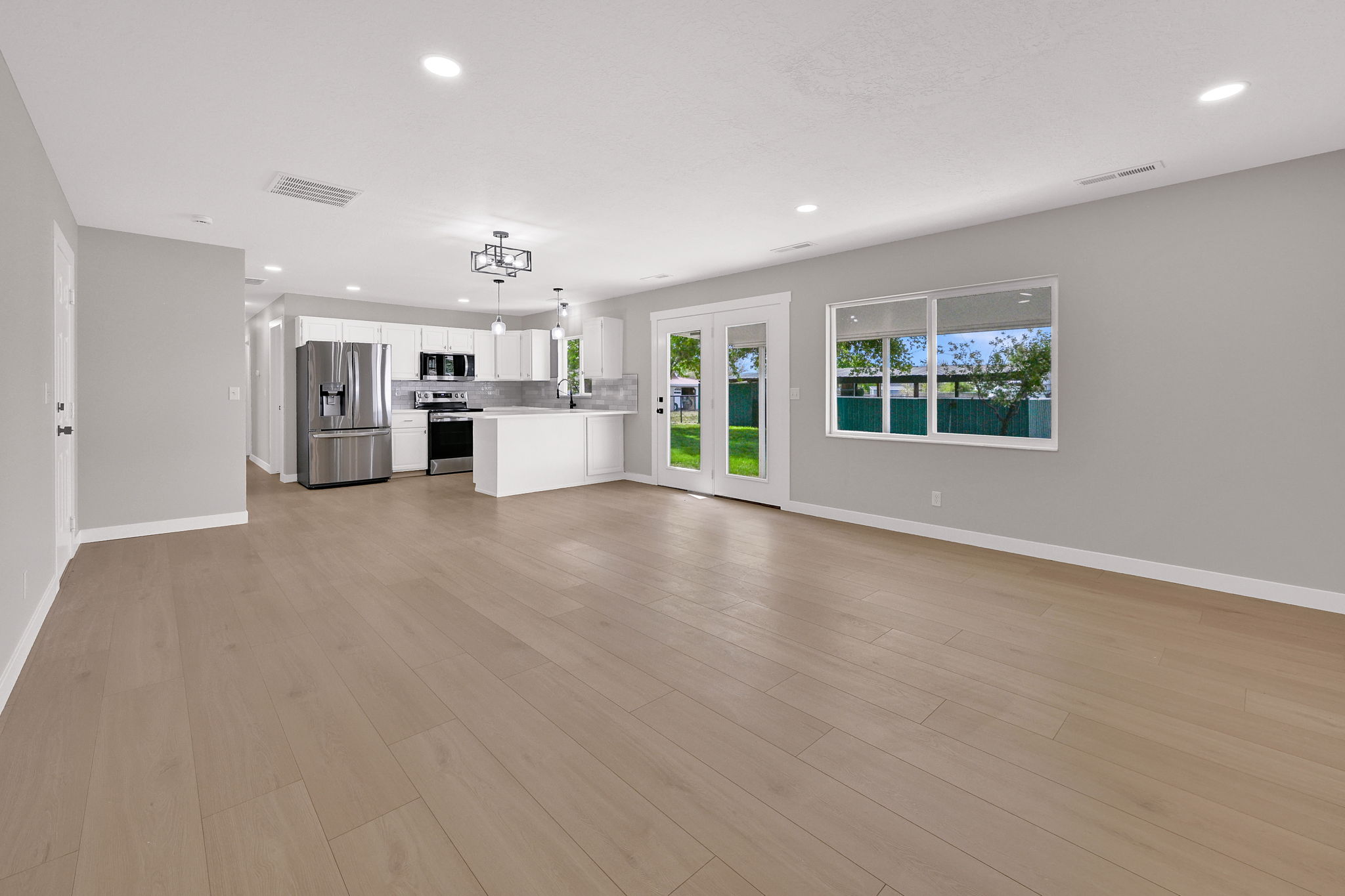 Open-concept living space with light wood-finish flooring, recessed lighting, and a neutral wall palette