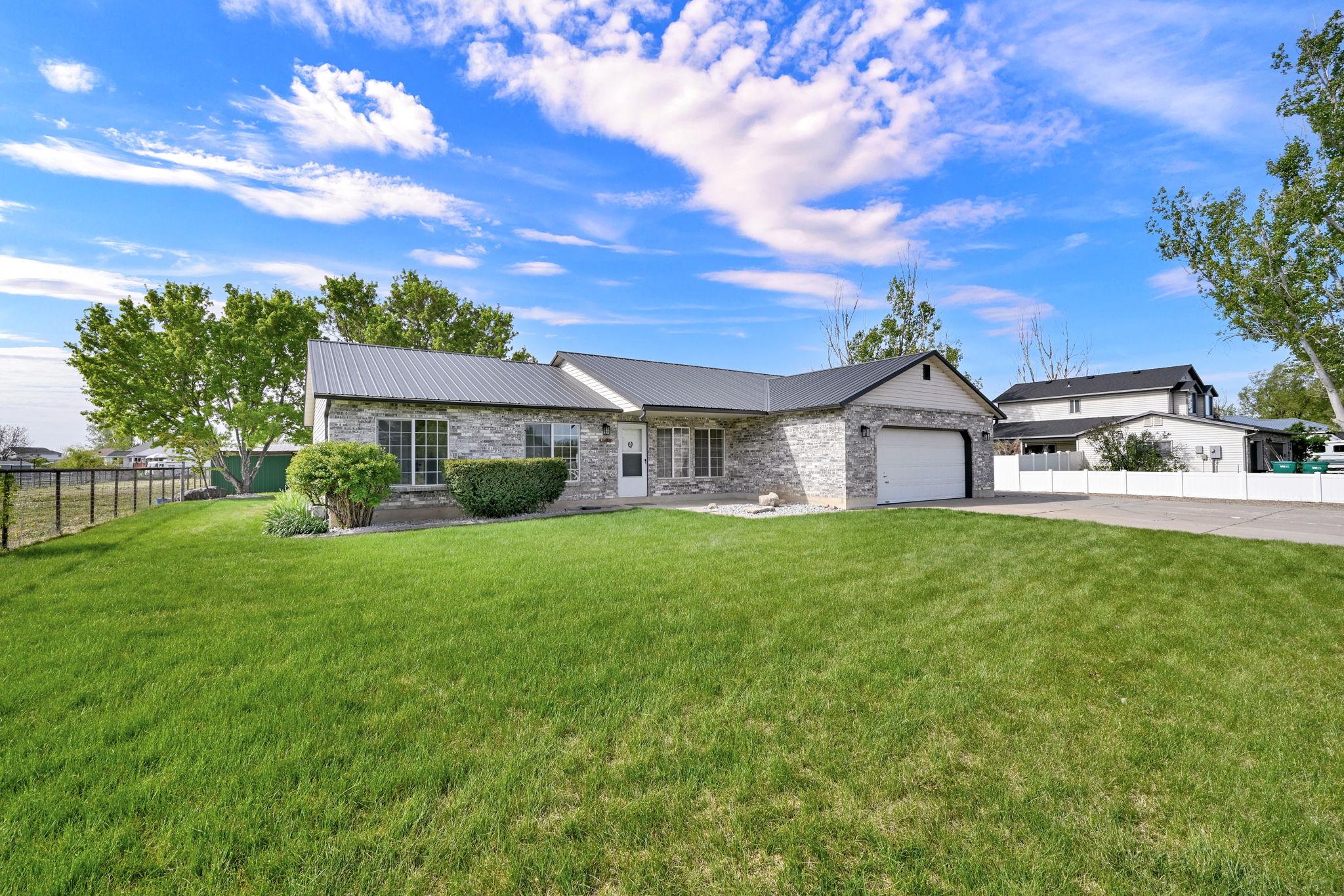 Single-story residence featuring a stone veneer exterior, a dark metal roof, and an attached two-car garage