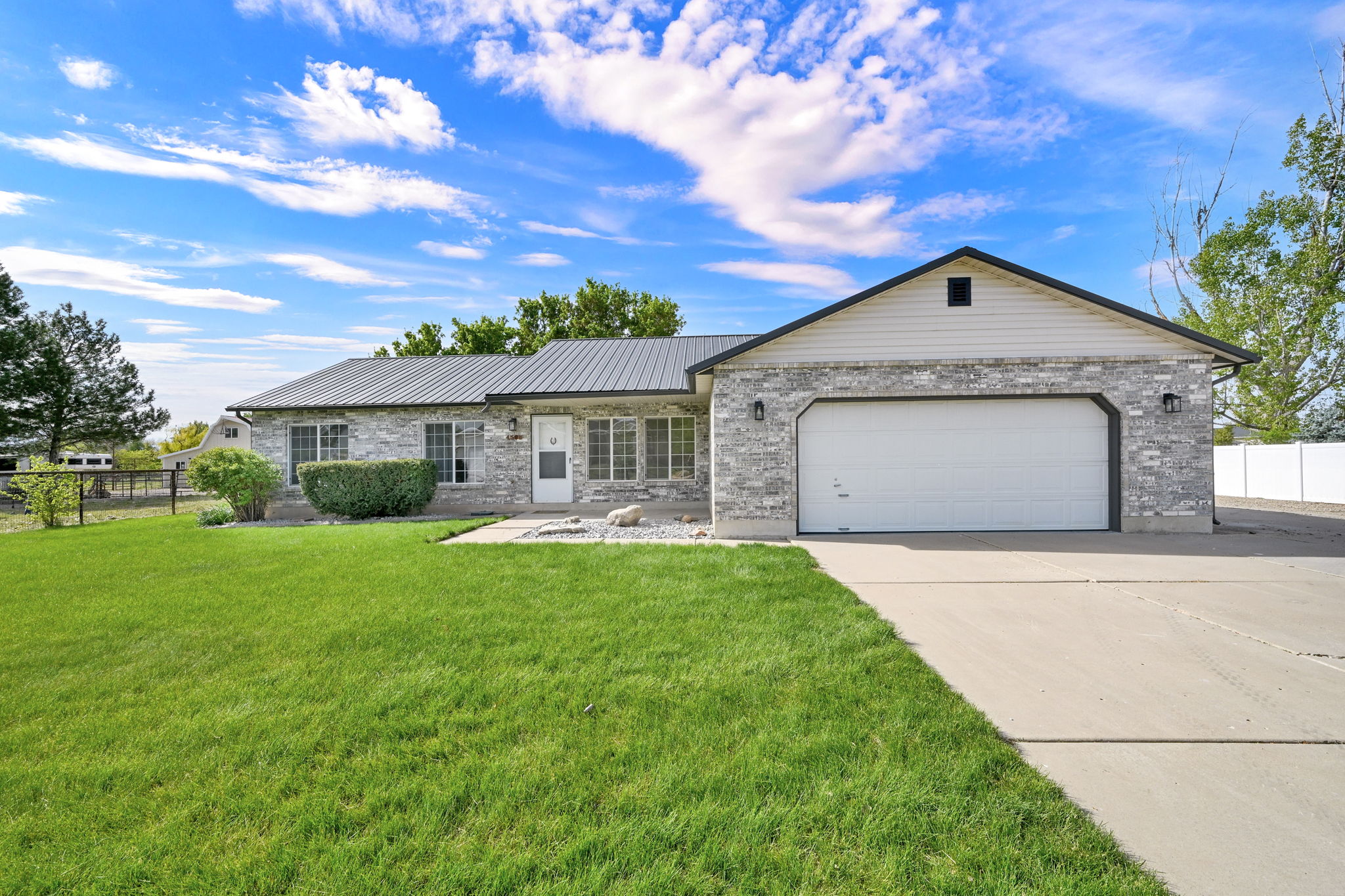 Ranch-style exterior featuring stone veneer siding and a dark metal roof