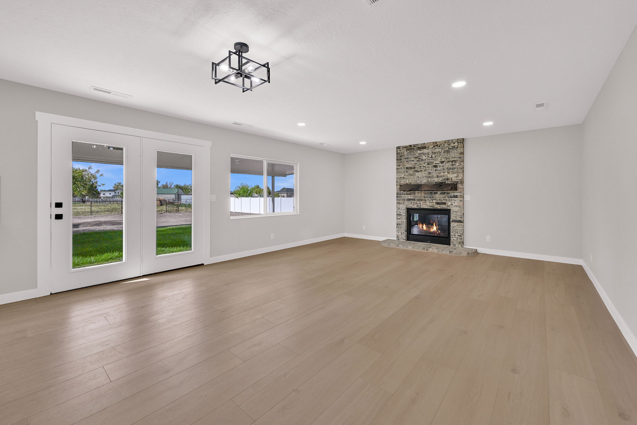 Spacious interior featuring wide plank wood-finish flooring, a stone-clad fireplace with a wood mantle, and recessed lighting