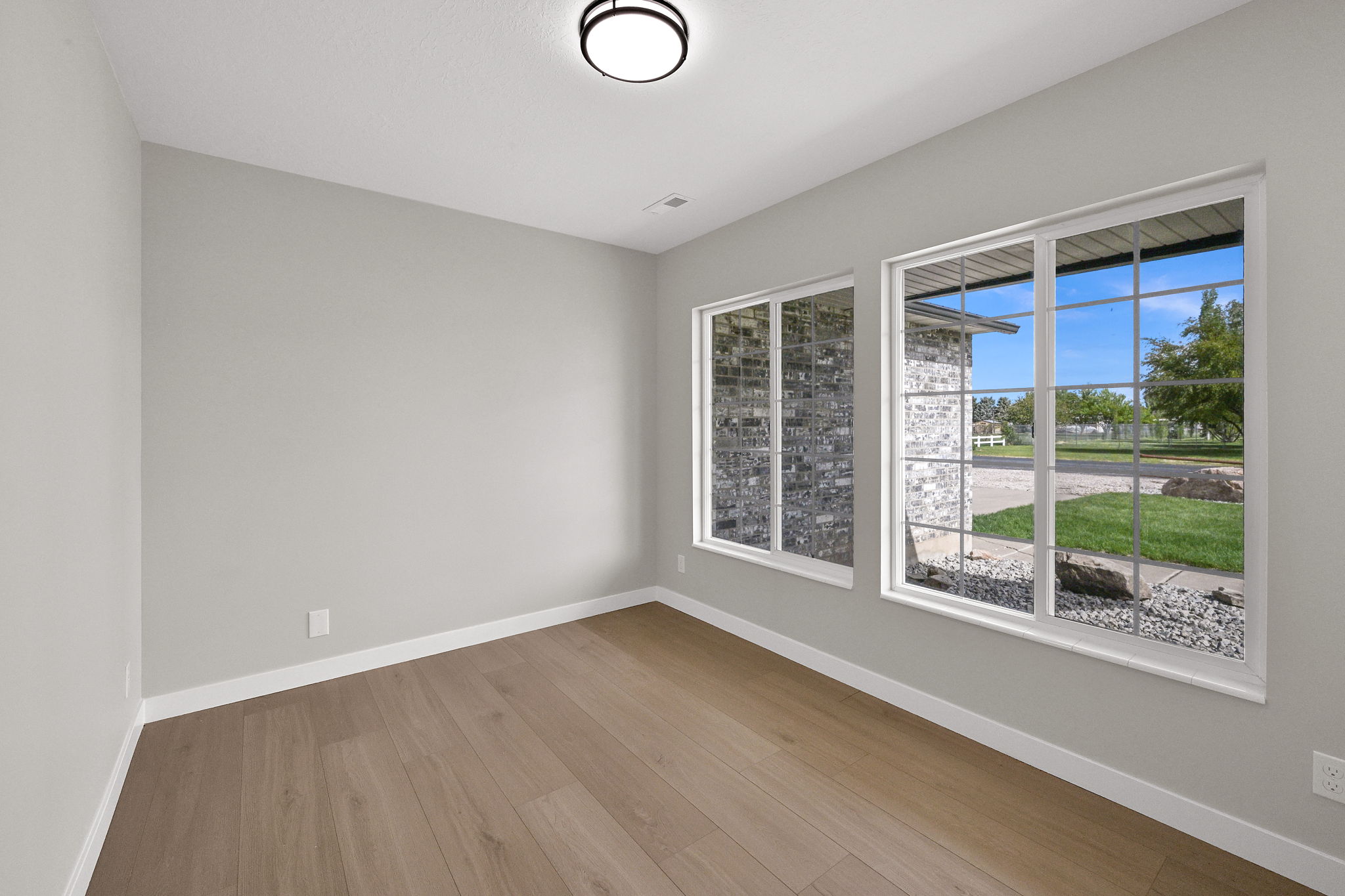 Room featuring wood-finish flooring, two large windows with grid patterns, and a flush-mount ceiling light fixture