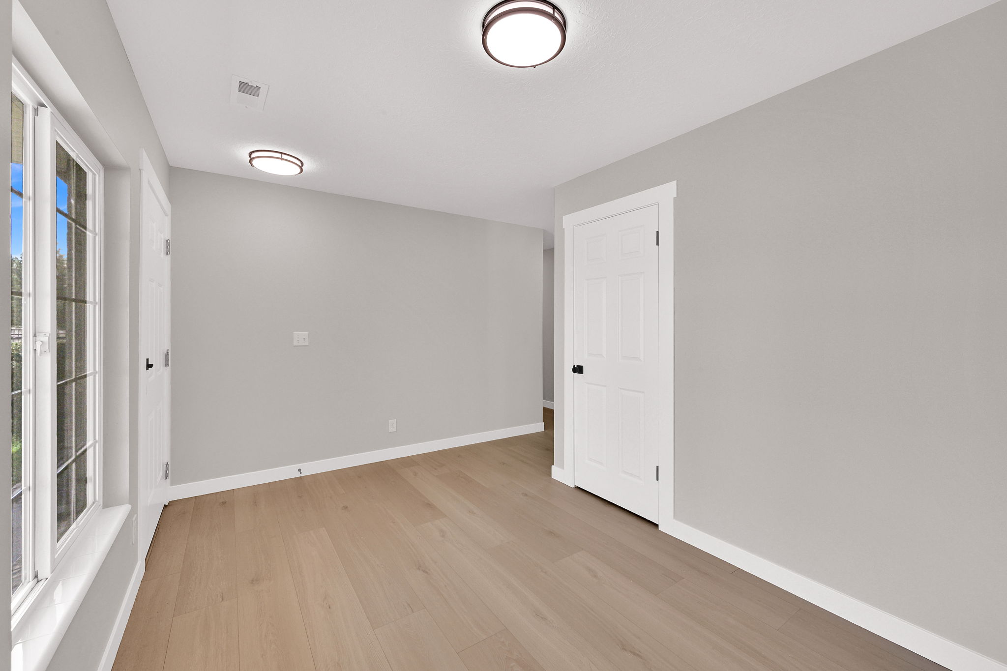 Open room featuring wood-finish flooring, light gray wall paint, and white trim