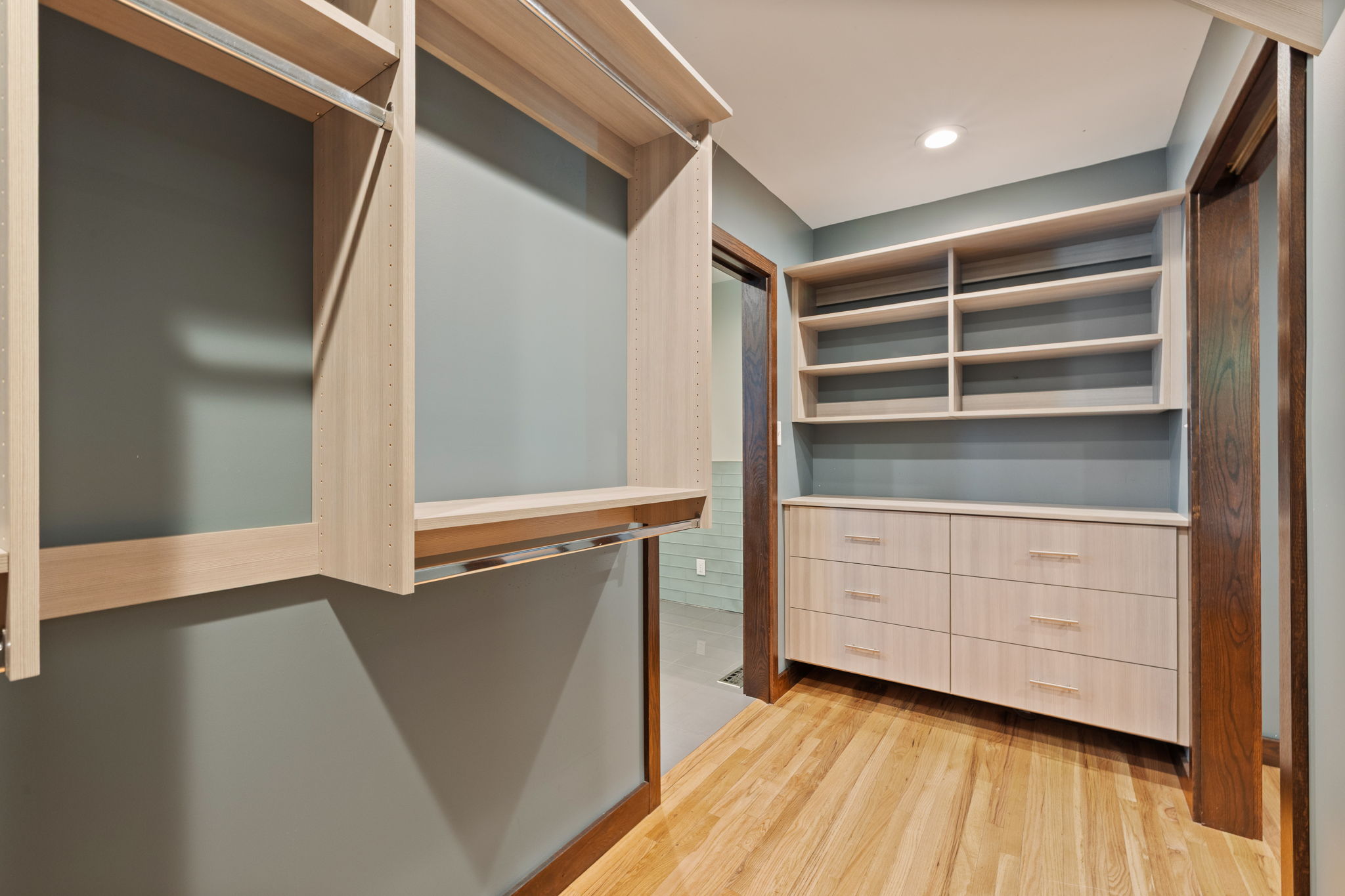Custom closet system featuring light wood-finish shelving and hanging rods