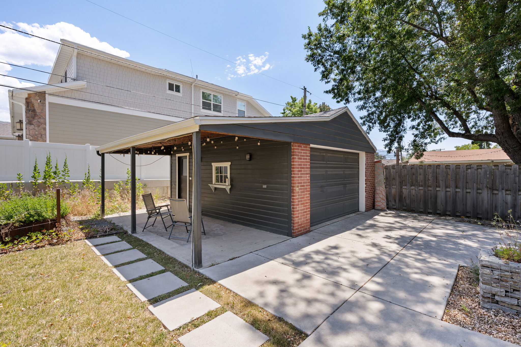 Detached garage featuring brick and siding accents, an attached covered patio with a concrete slab, and a concrete driveway