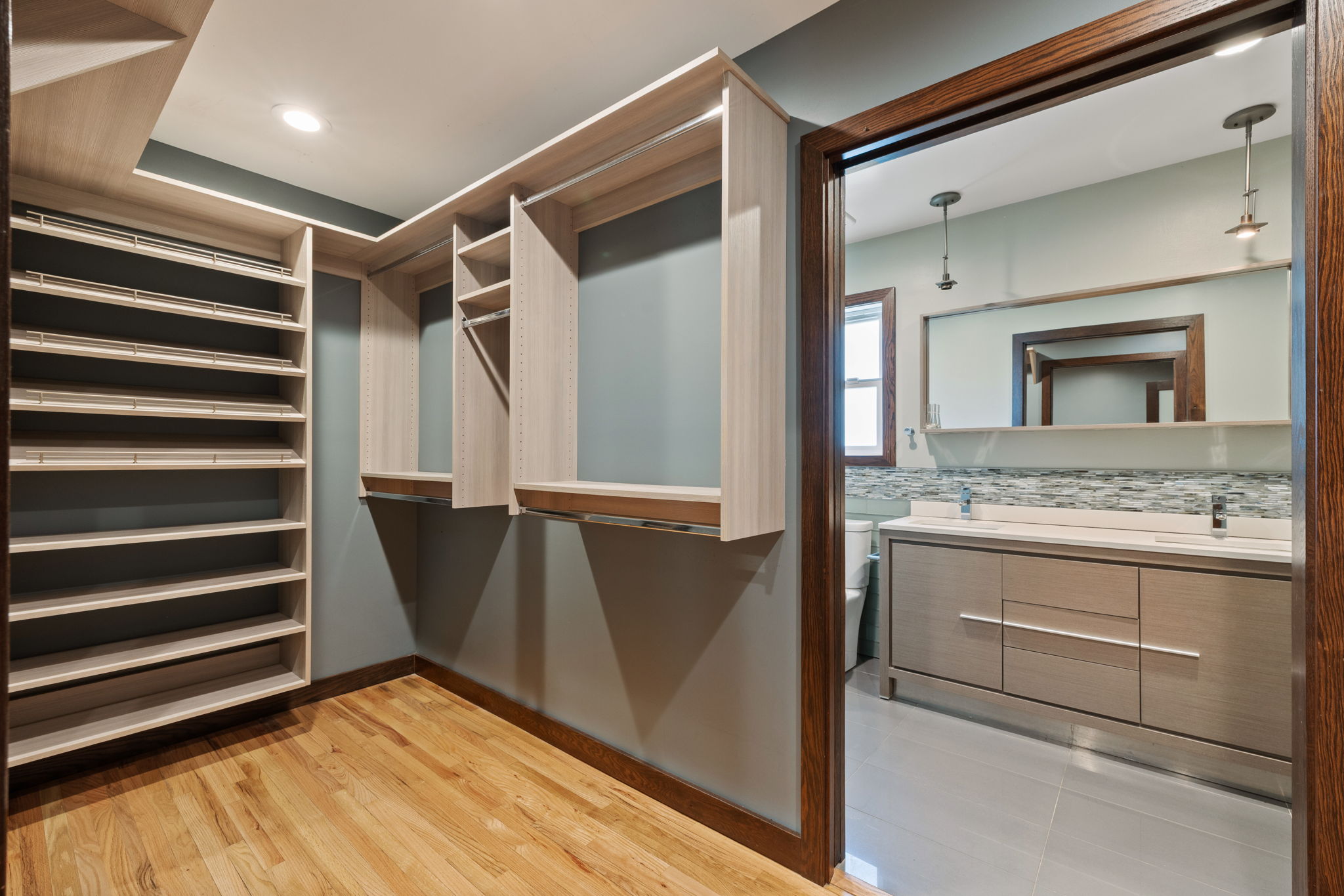Custom closet system with light-tone wood-finish shelving and hanging rods