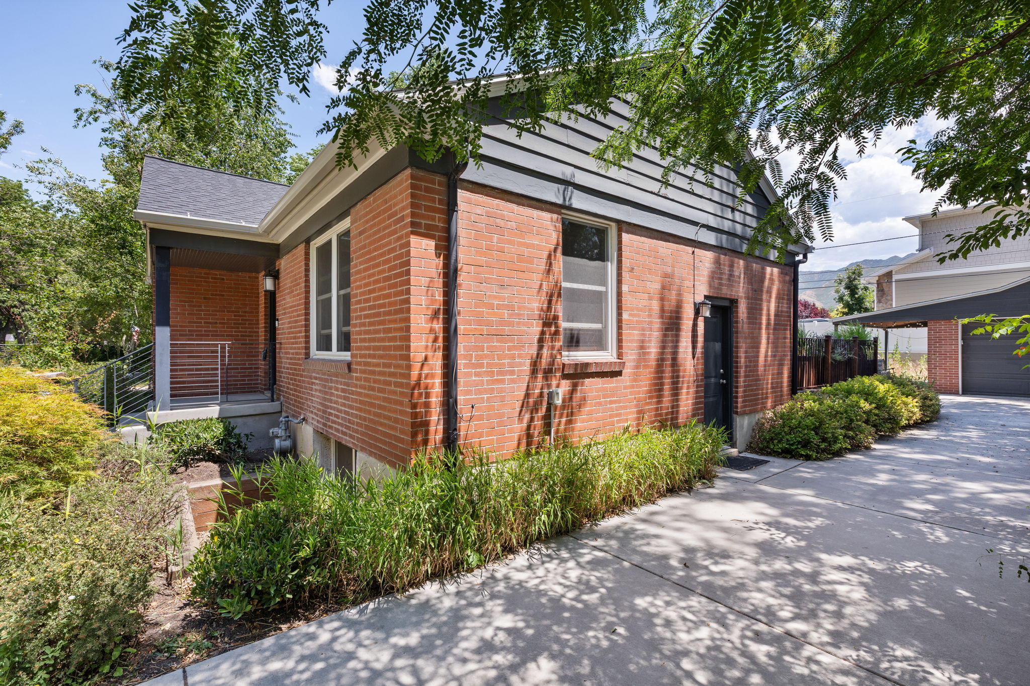 Brick exterior with dark siding accents, featuring a covered porch entry and a paved driveway