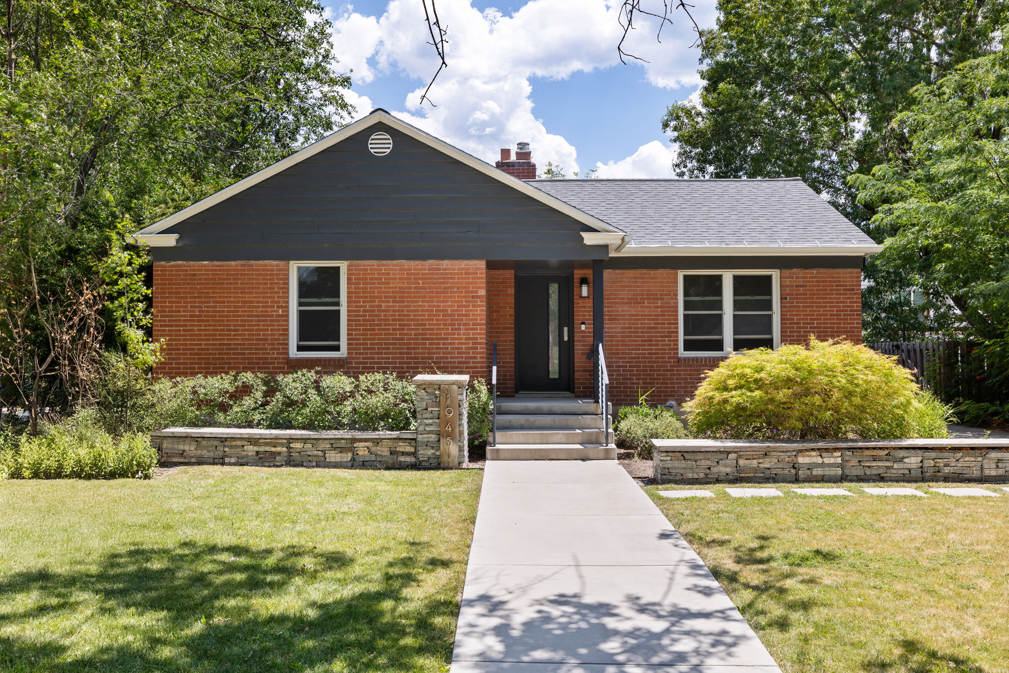 Brick facade home featuring a contrasting dark siding gable