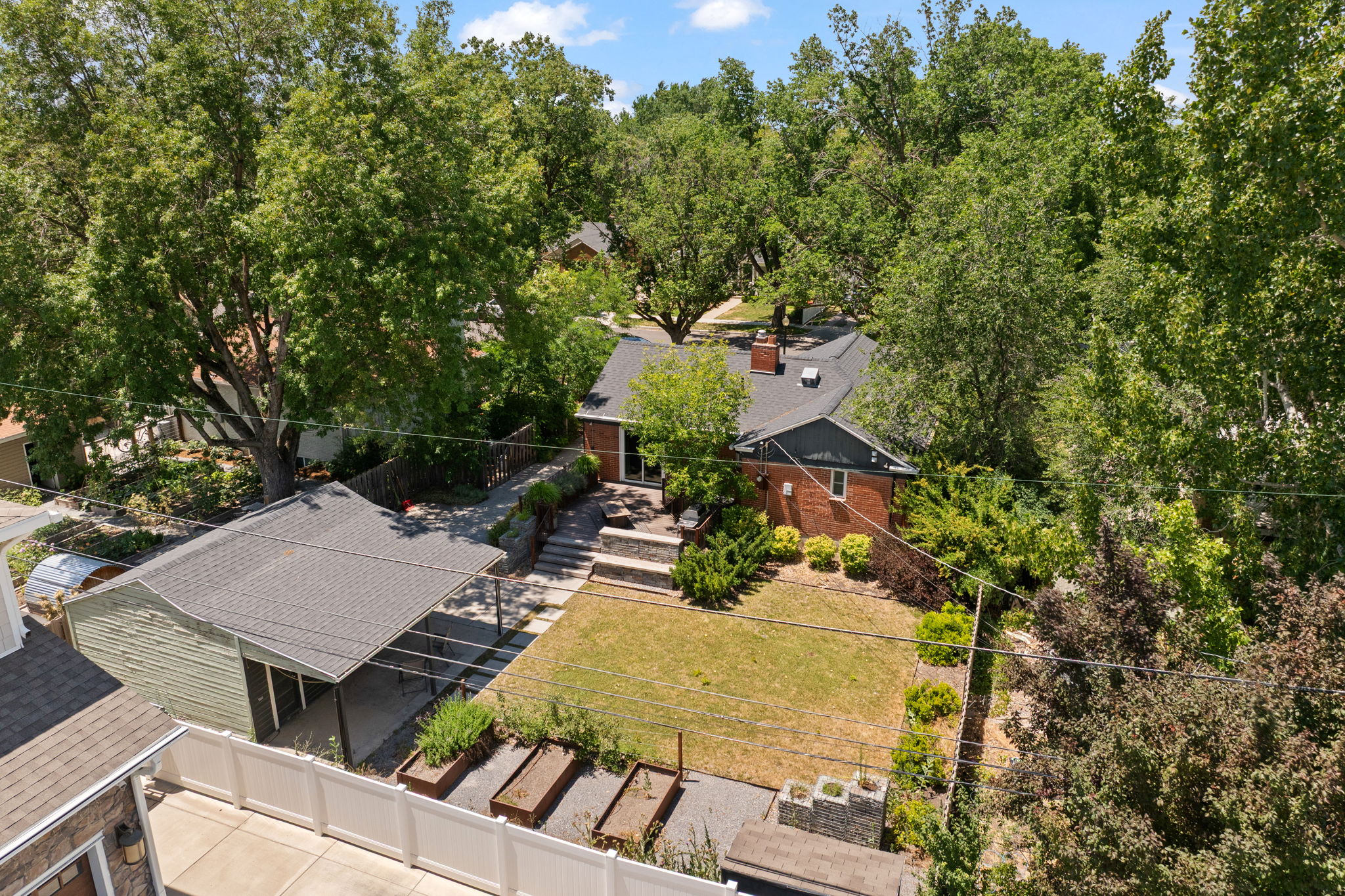 Expansive backyard featuring a manicured lawn, established landscaping, and raised garden beds
