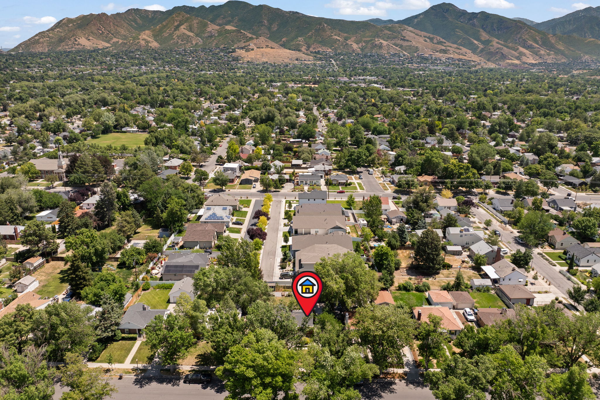 Aerial perspective showcasing a residential area with mature trees and mountain backdrop